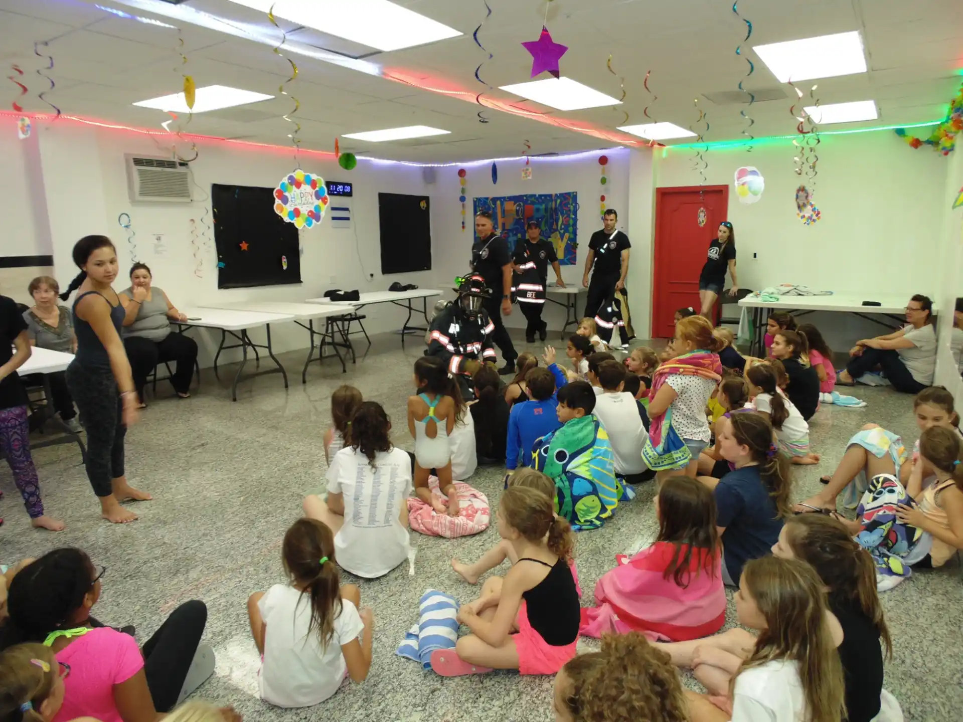 a group of people sitting in a room with a person playing a guitar
