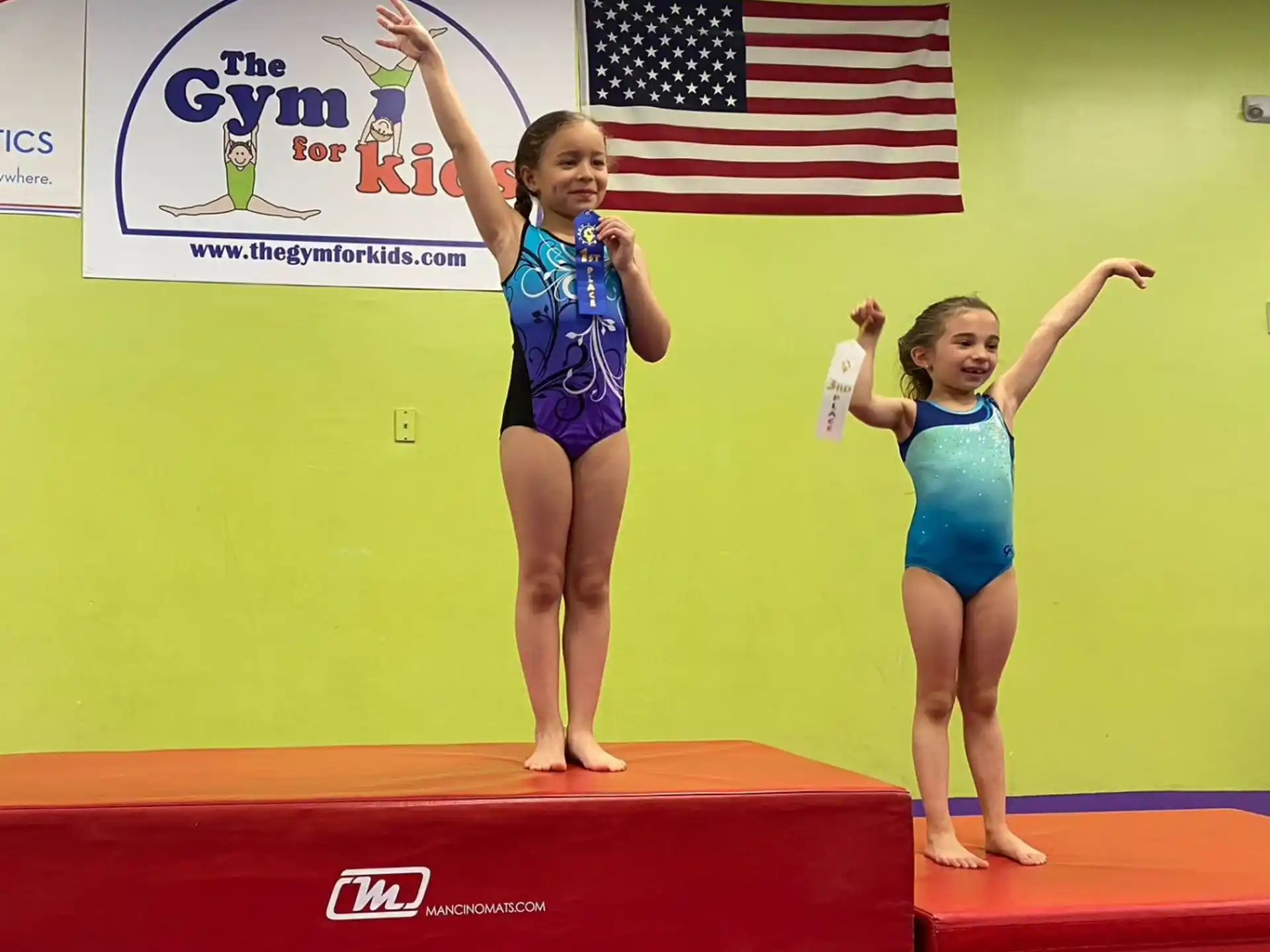 a group of girls in swimsuits on a podium with a flag
