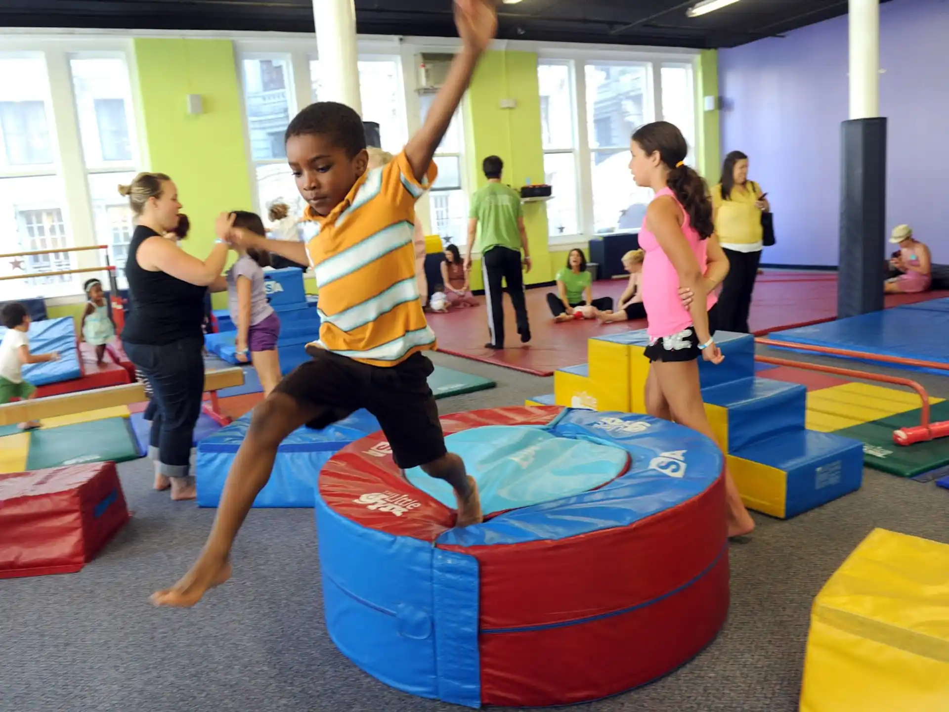 a group of people playing on a mat in a room with a large window
