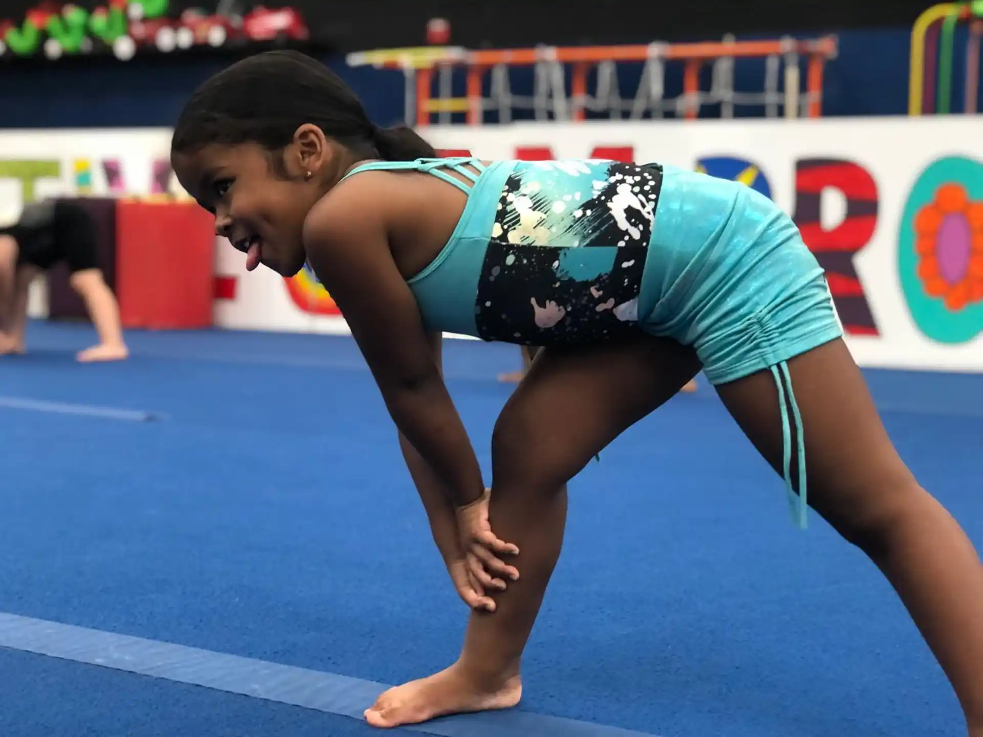 a woman in a leotard doing a handstand on a blue mat