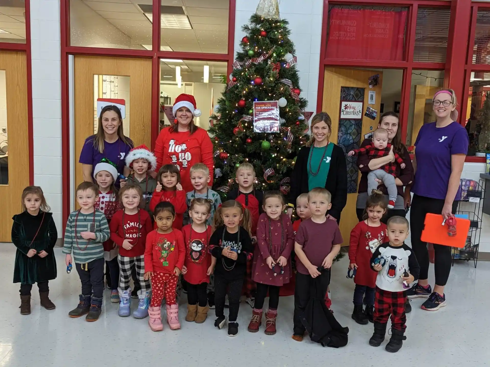a group of children posing for a photo in front of a christmas tree