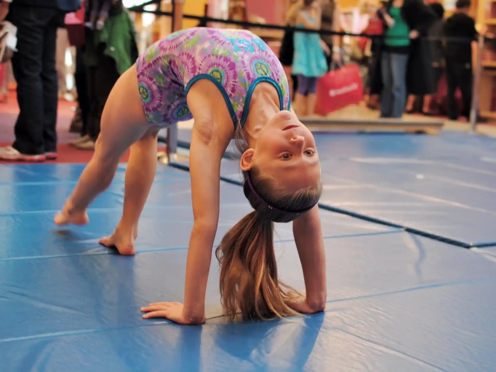 a girl doing a handstand on a blue mat