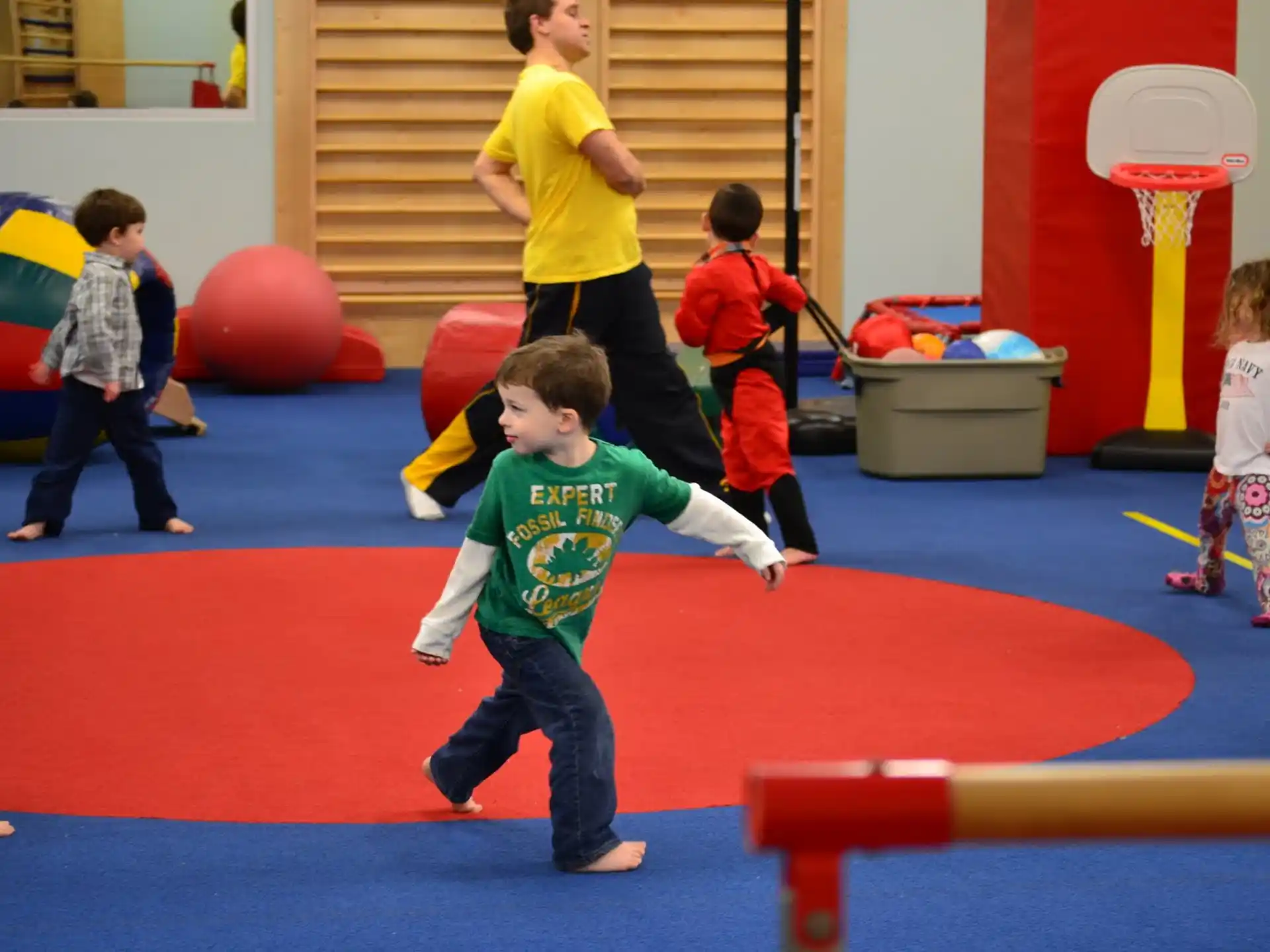 a group of children playing on a red mat in a room