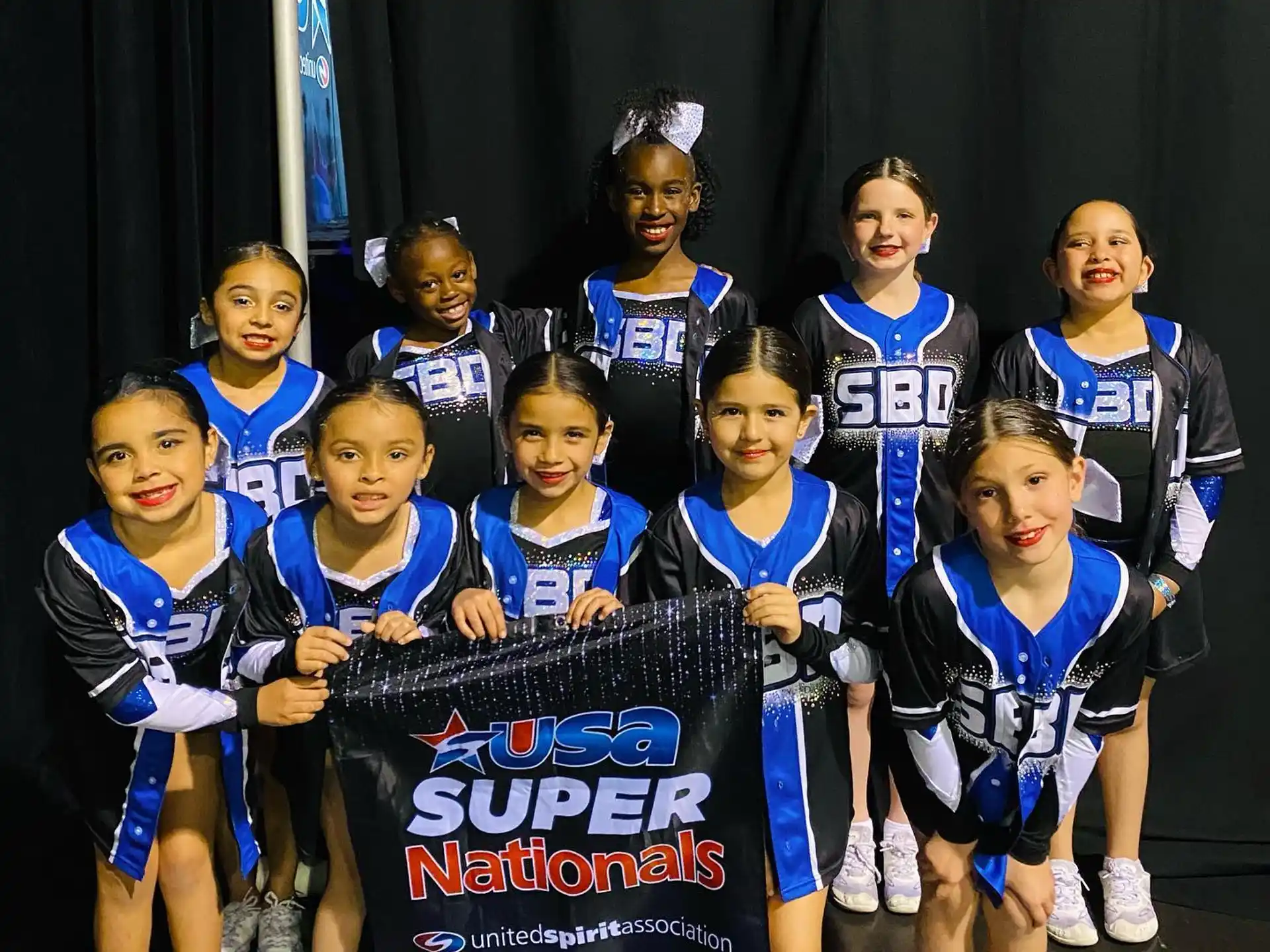 a group of girls in blue uniforms holding a sign