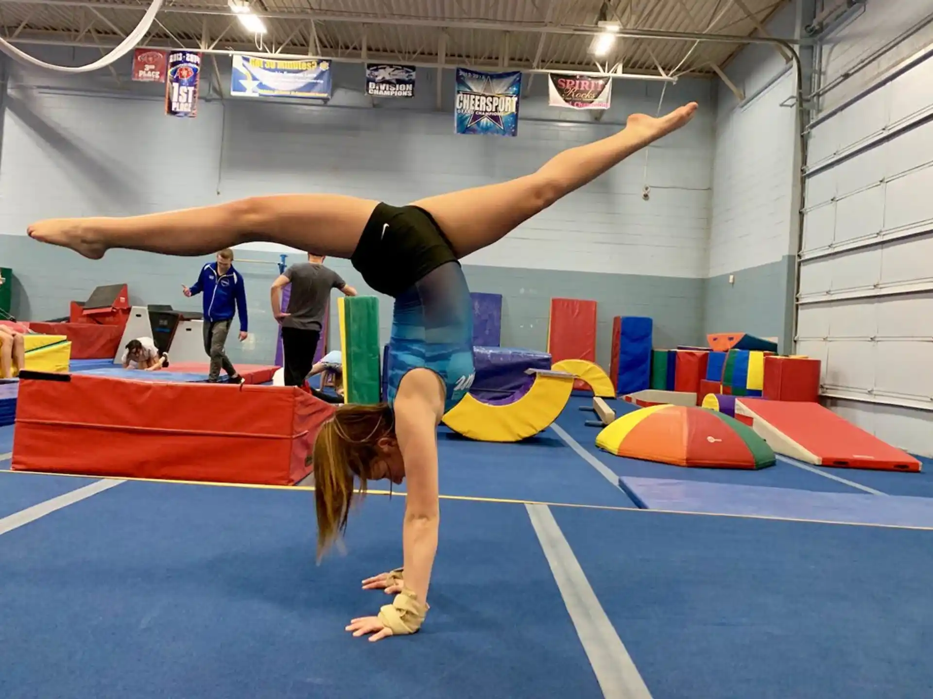 a person doing a handstand on a mat in a gym
