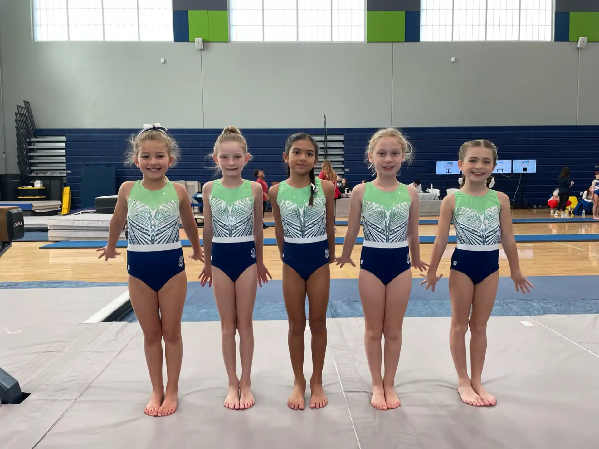 a group of girls in swimsuits standing in front of a swimming pool