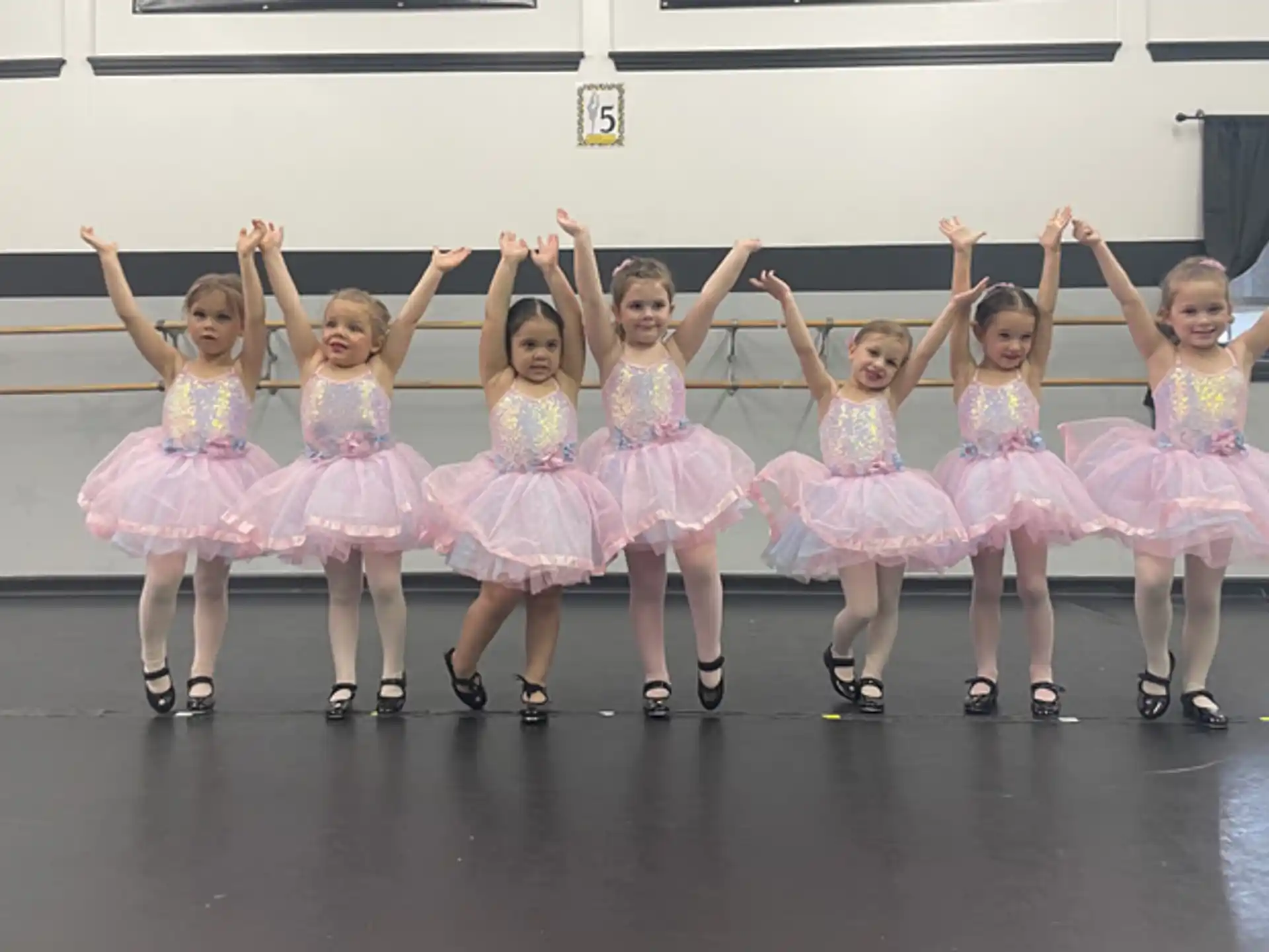 a group of girls in dresses and skirts dancing on a stage