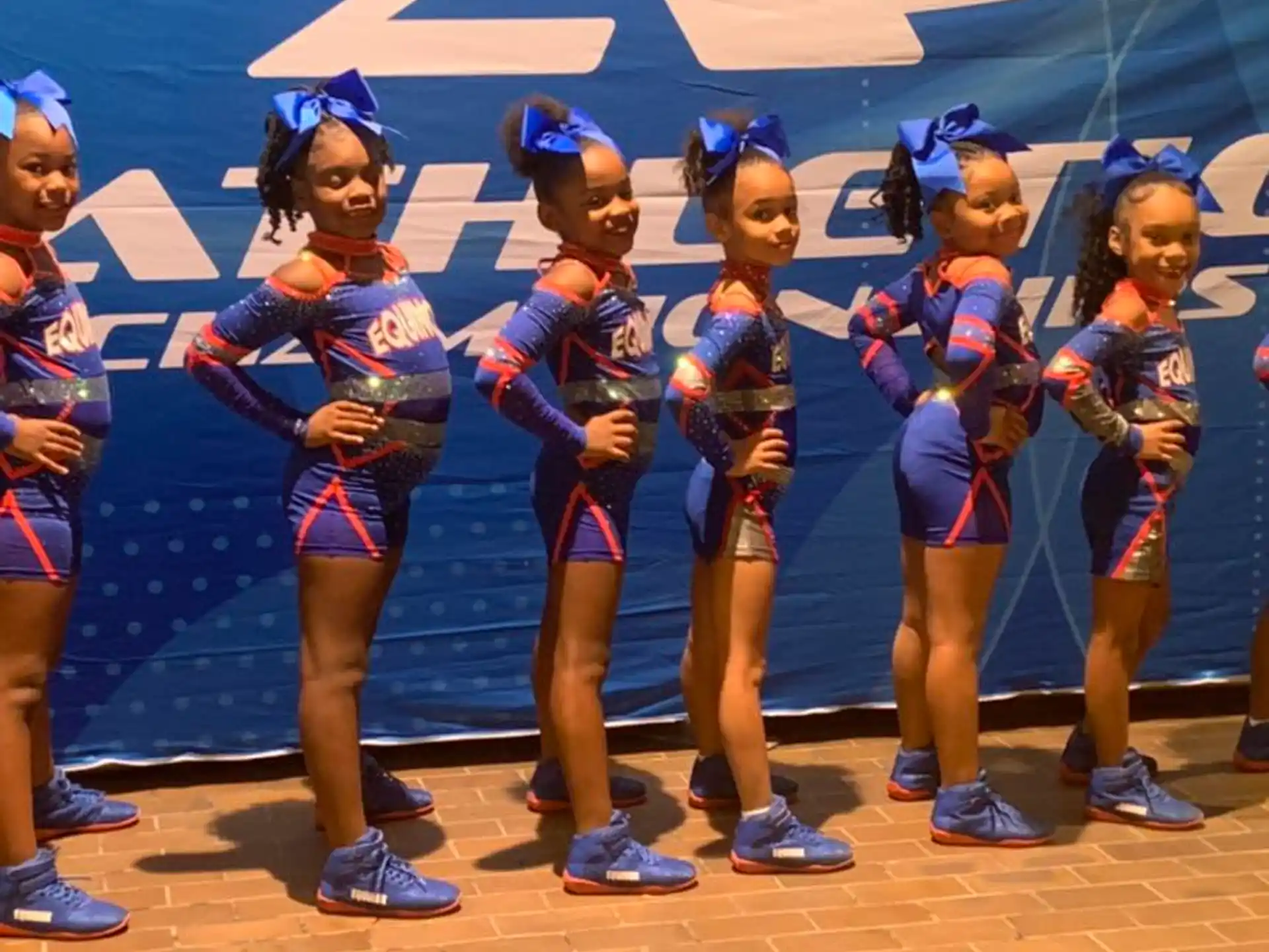 a group of girls in blue and red uniforms standing on a brick surface