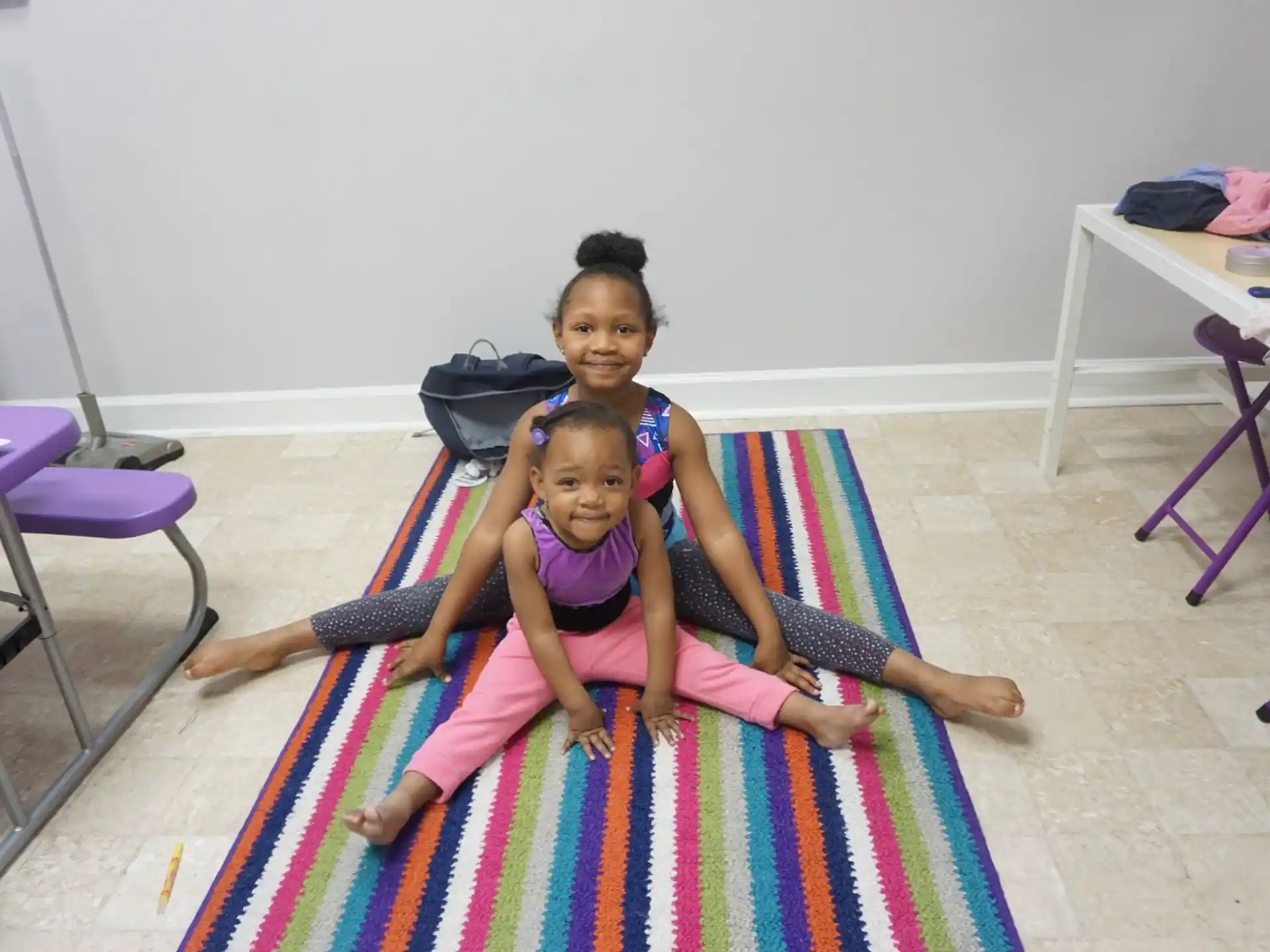 a person and a child sitting on a colorful mat in a room