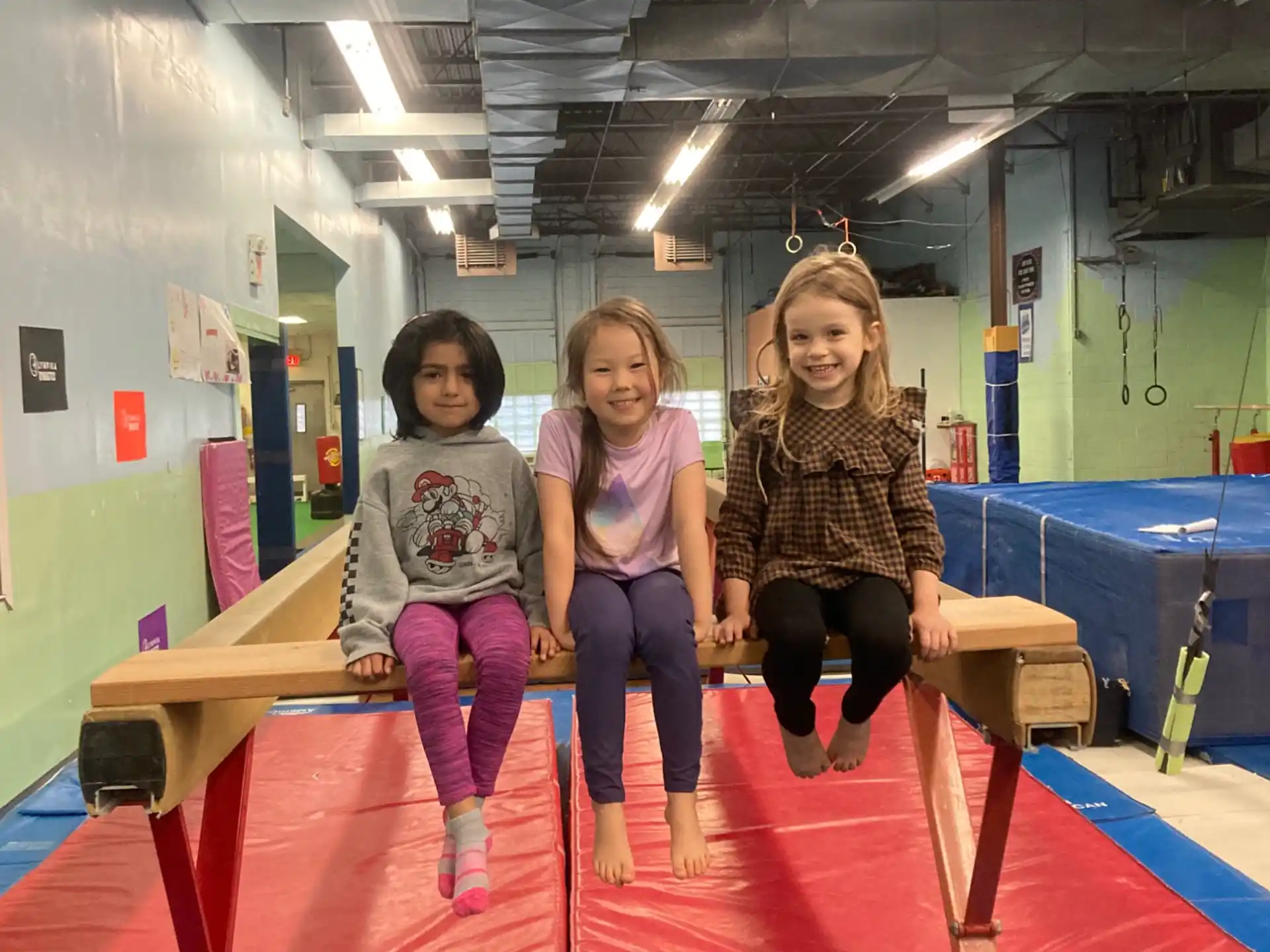 a group of girls sitting on a mat in a room with a blue mat and a green table