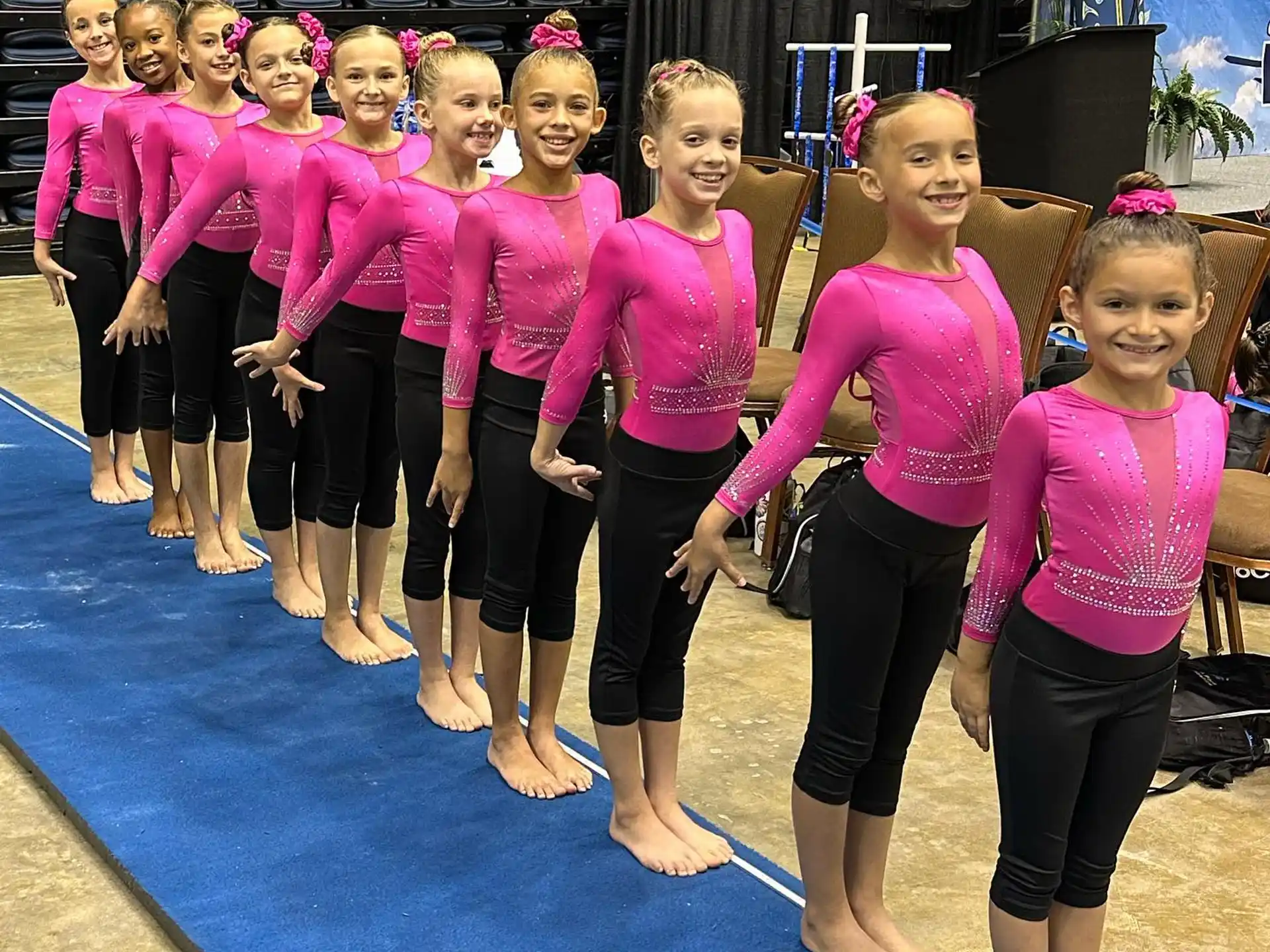 a group of girls in matching pink shirts and black pants