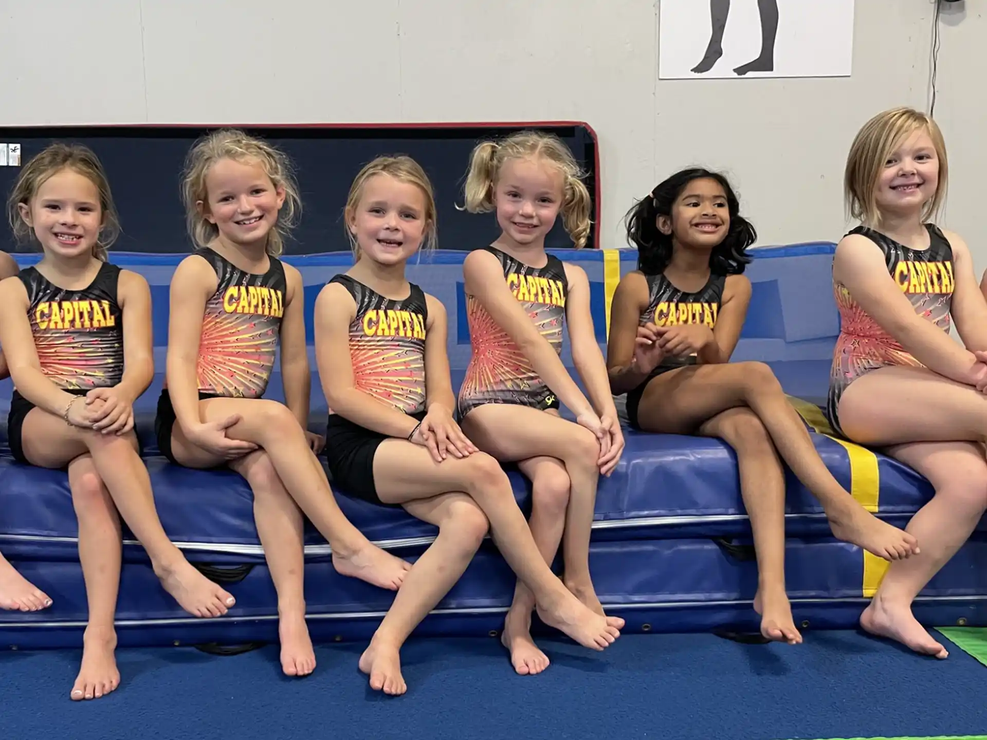 a group of girls in swimsuits sitting on a mat