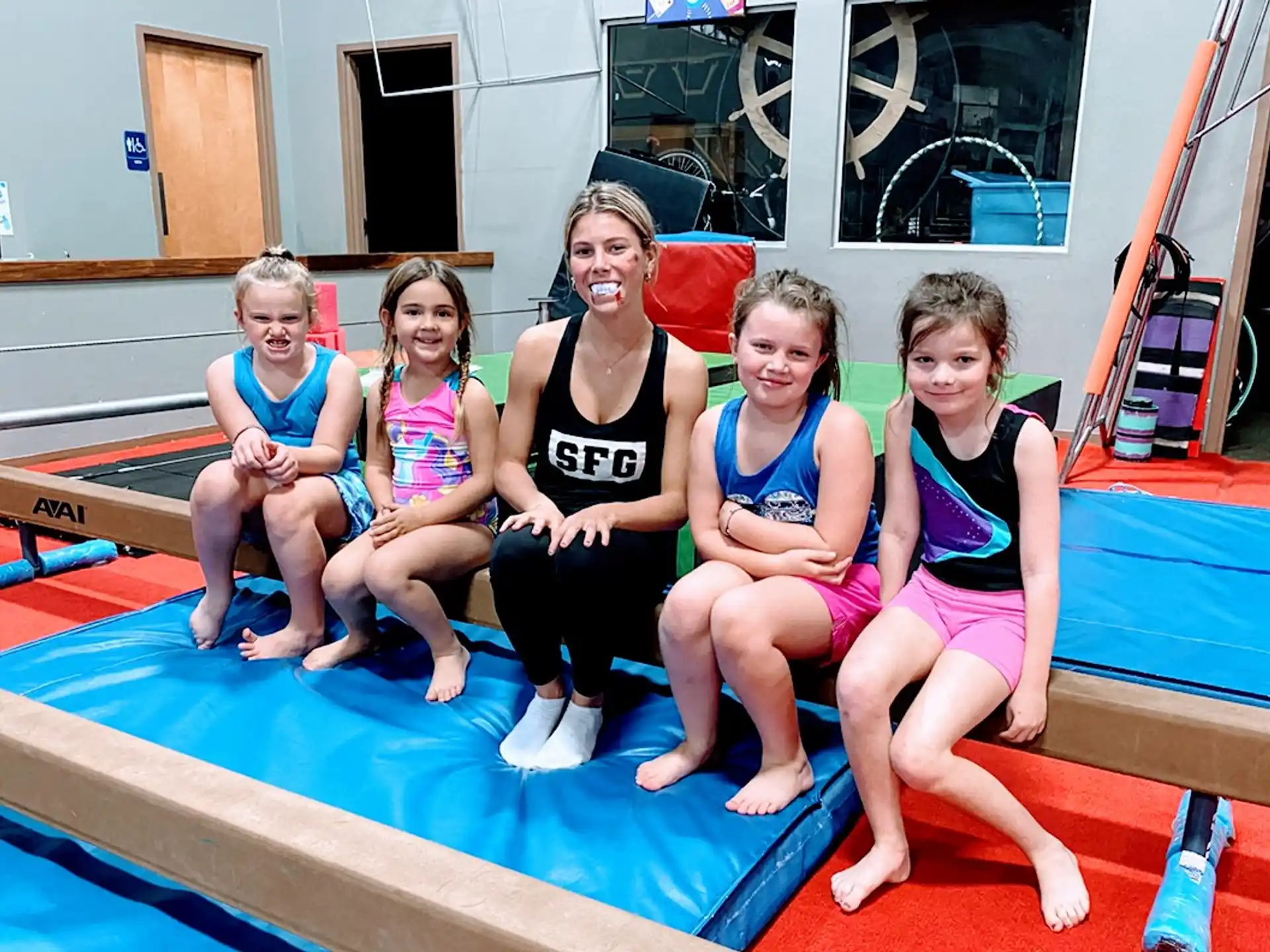 a group of girls sitting on a mat posing for the camera