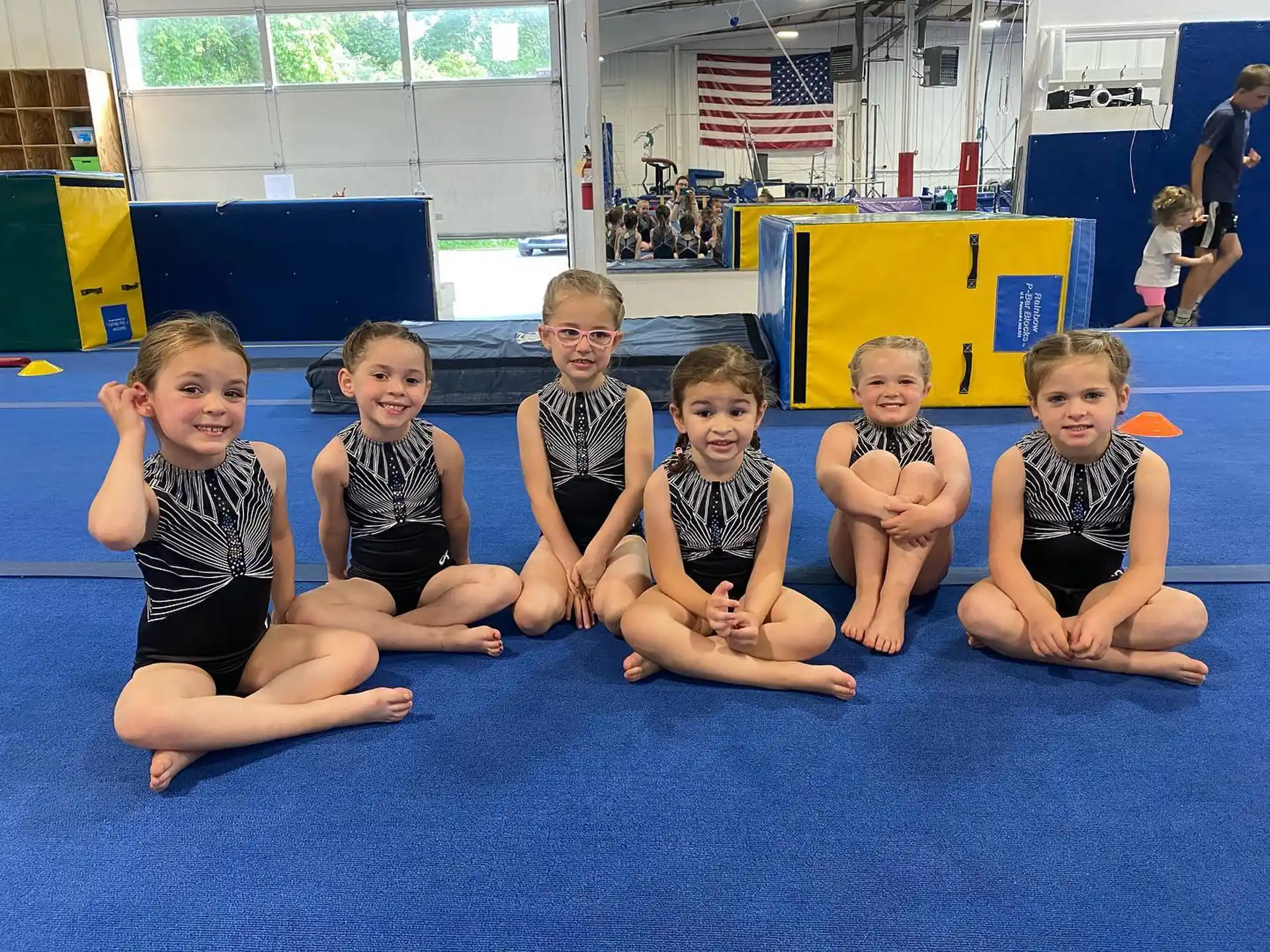 a group of children in swimsuits sitting on a mat