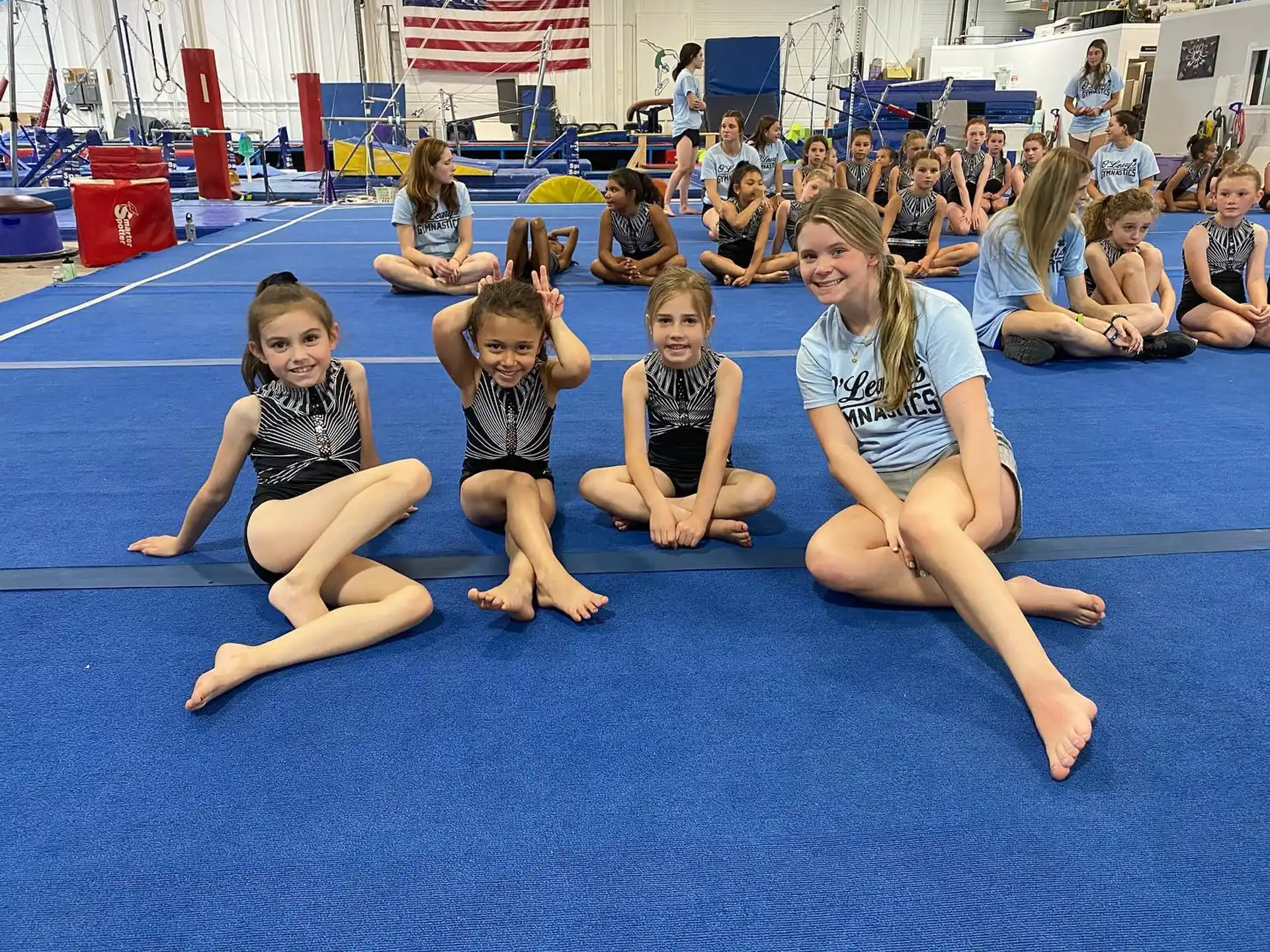 a group of children sitting on a mat in front of a crowd