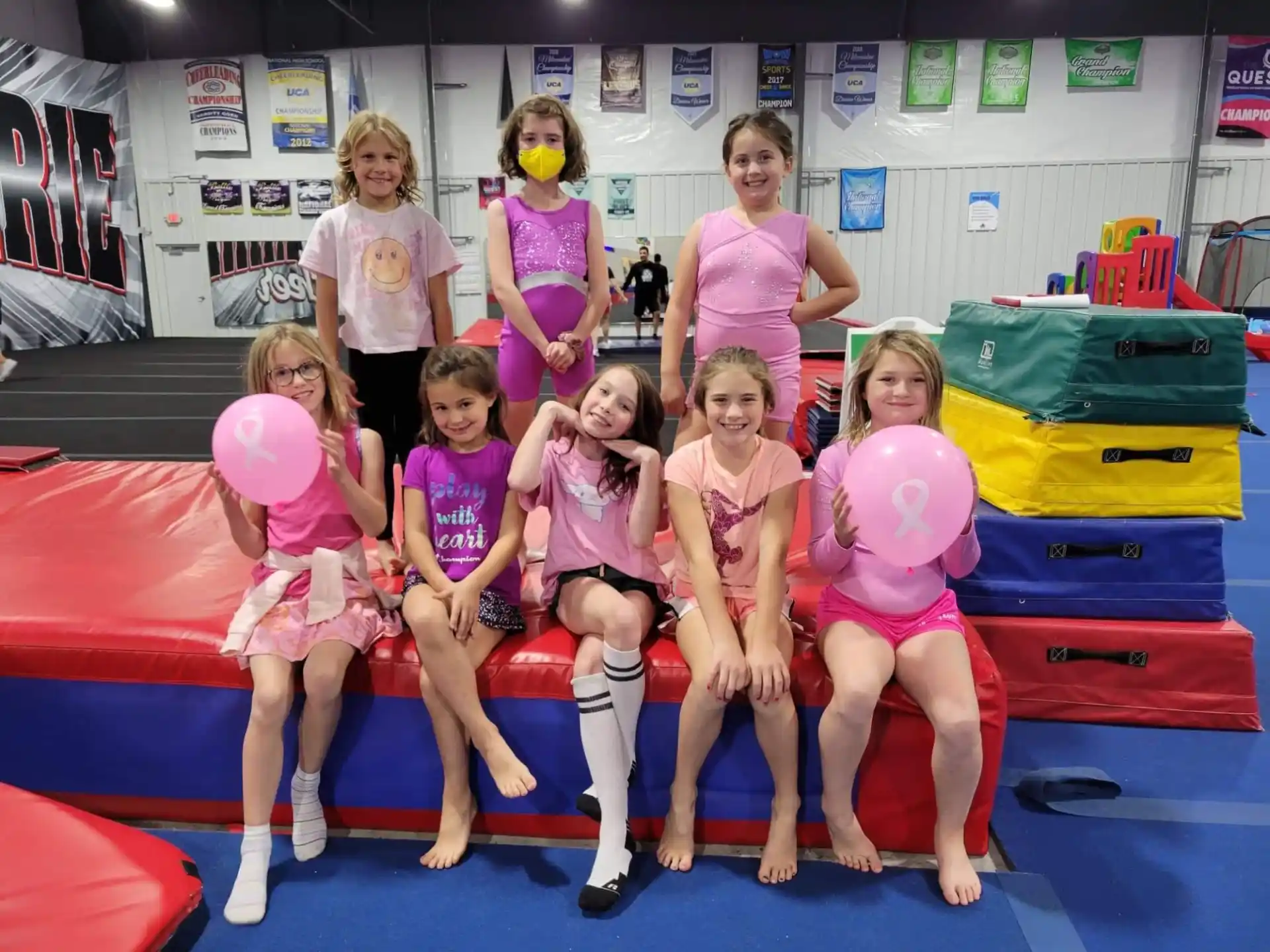 a group of girls in pink and white dresses on a trampoline