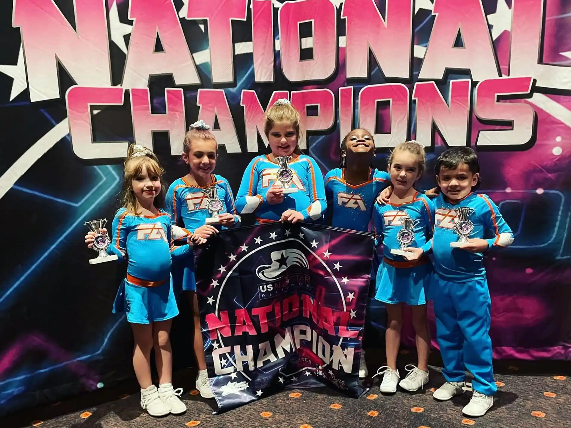 a group of children posing for a photo in front of a poster