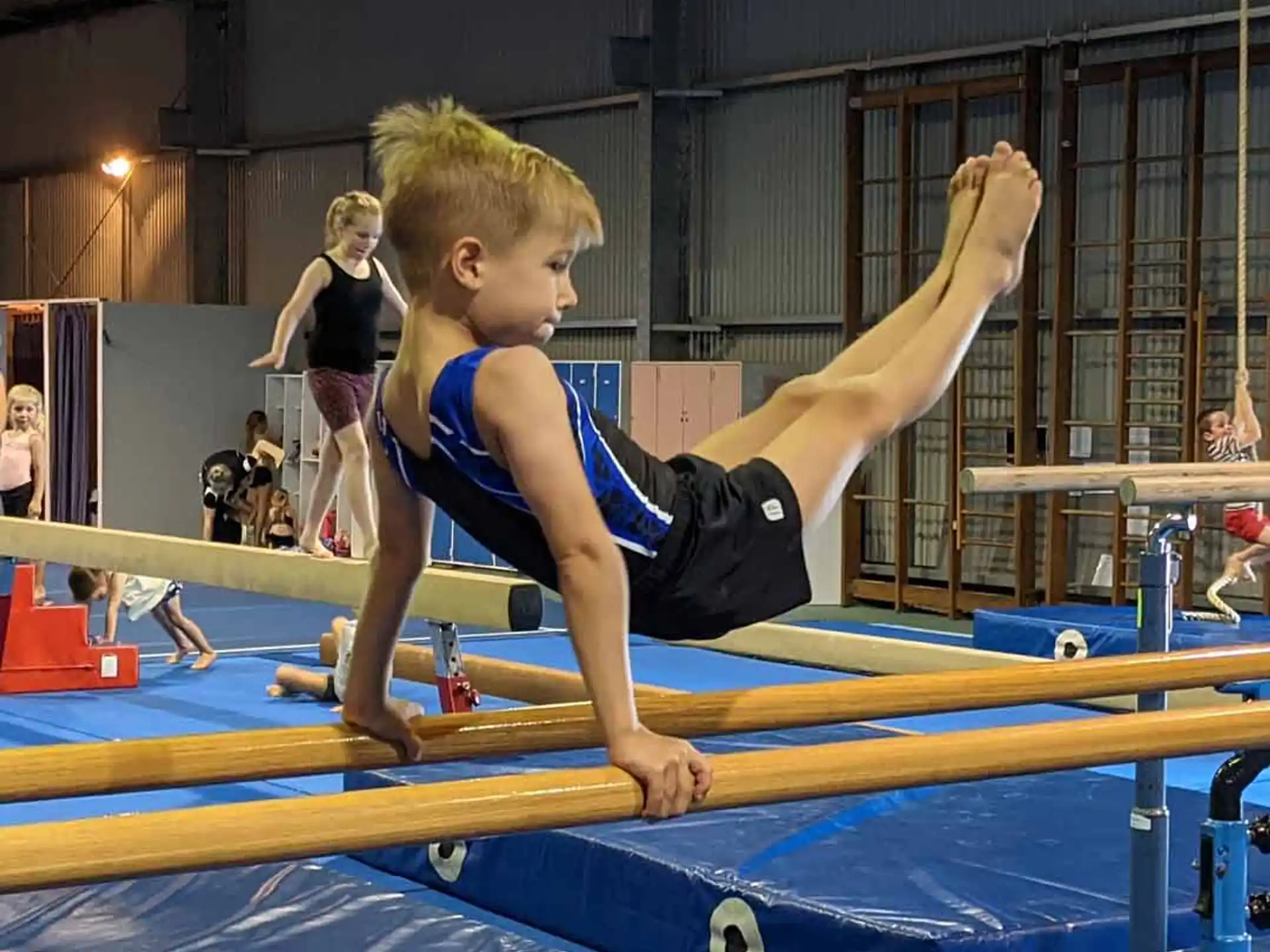 a boy doing a plank on a mat in a gym