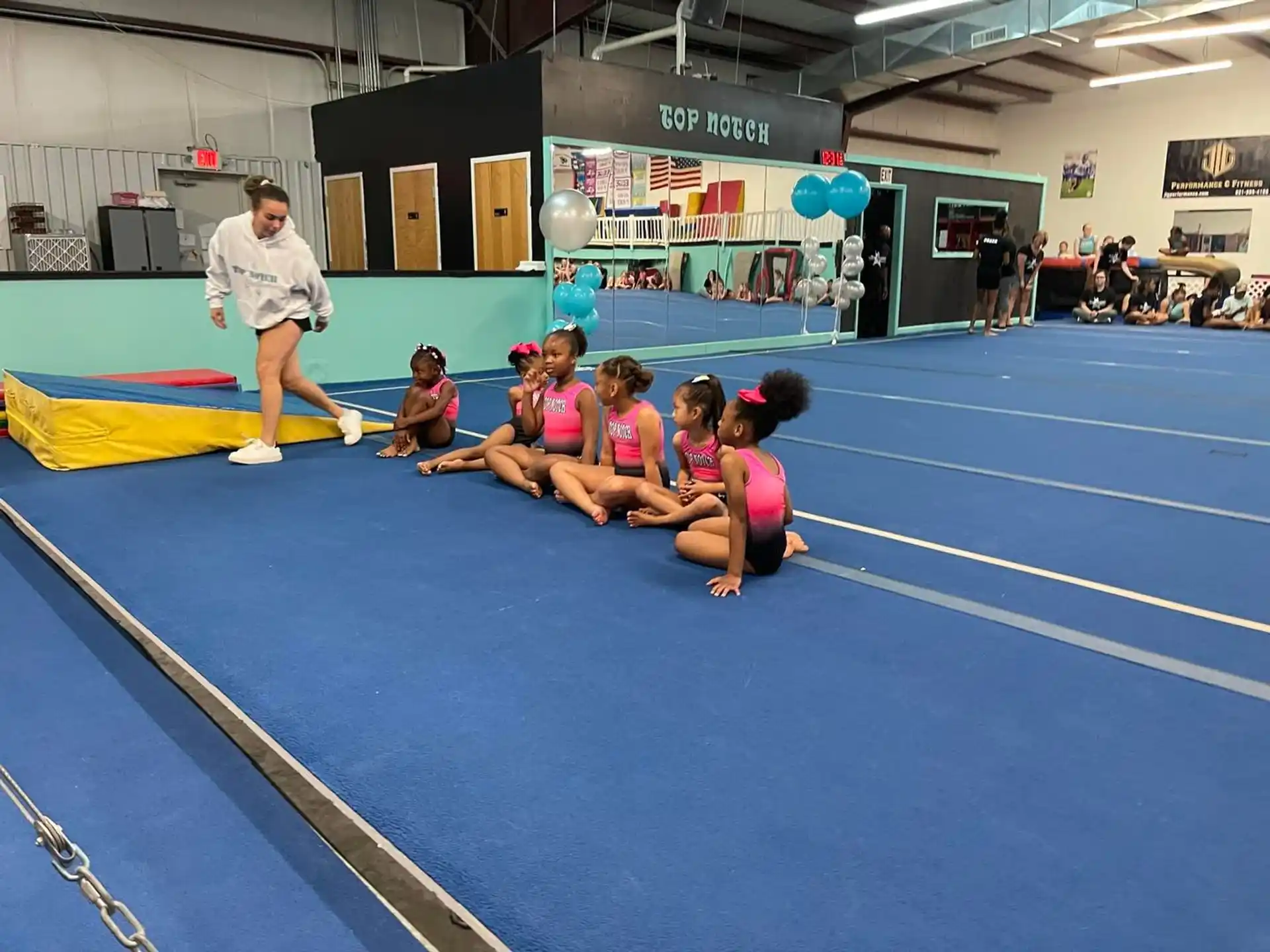 a group of people sitting on a blue mat in a gym