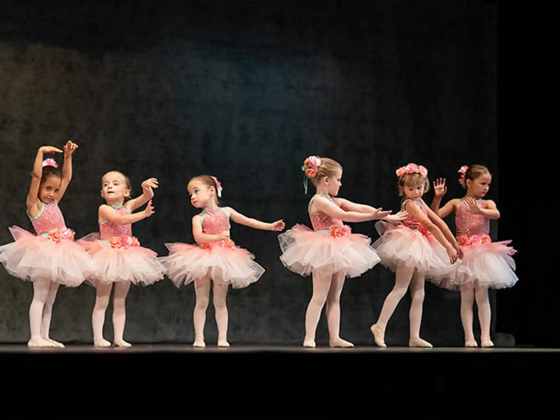 a group of girls in dresses on a stage