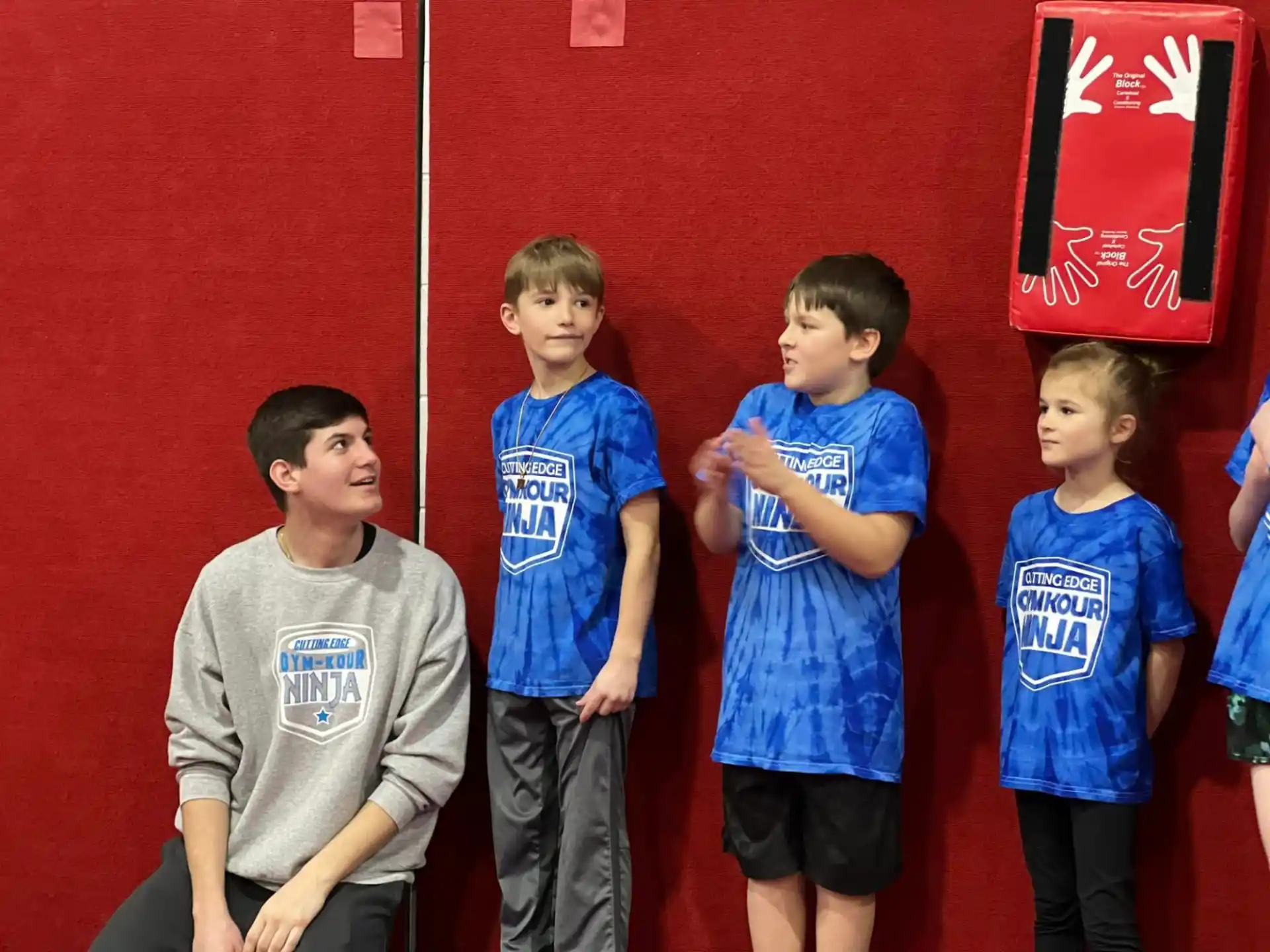 a group of boys standing in front of a red wall
