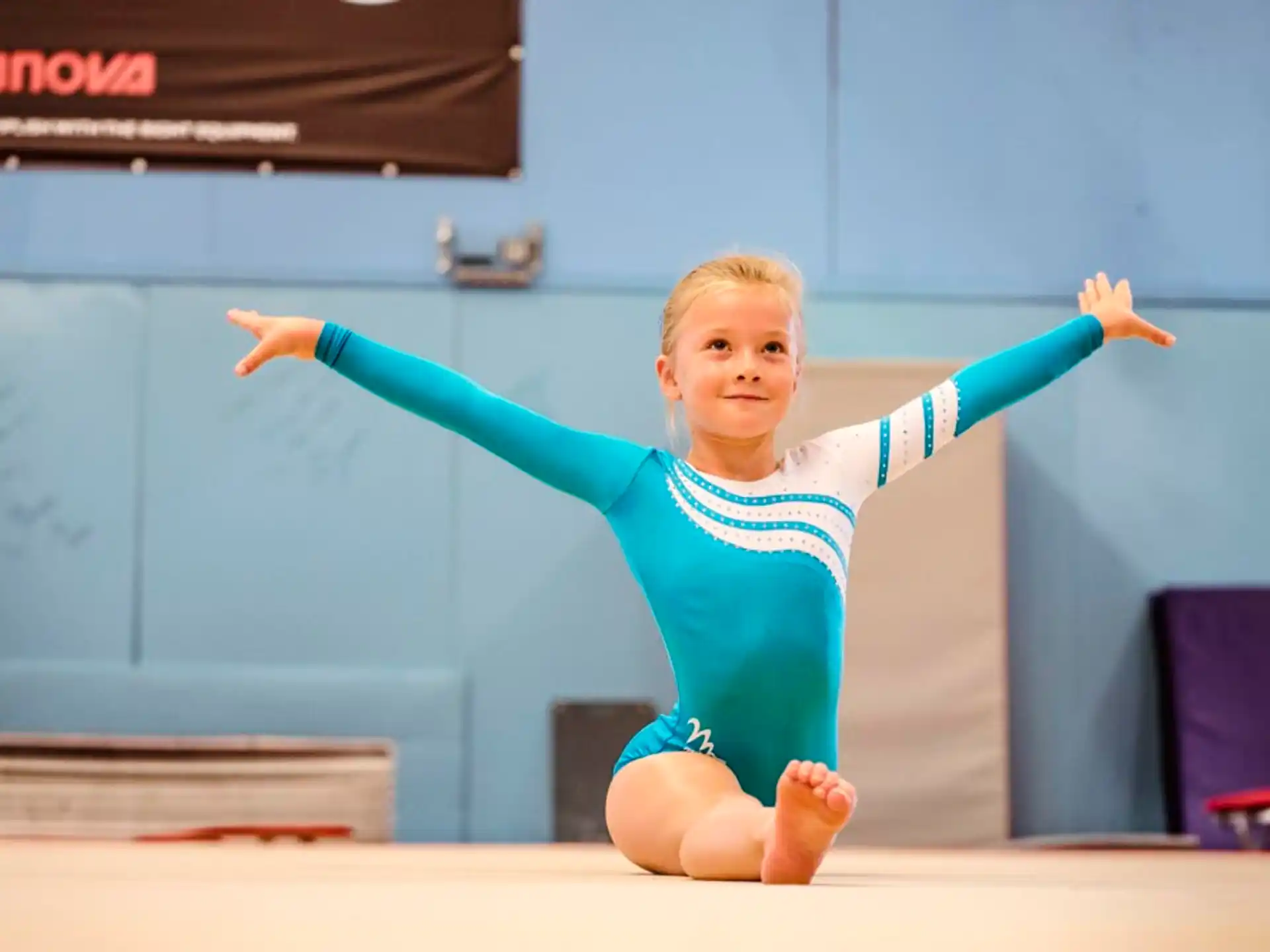a girl in a blue leotard on a stage