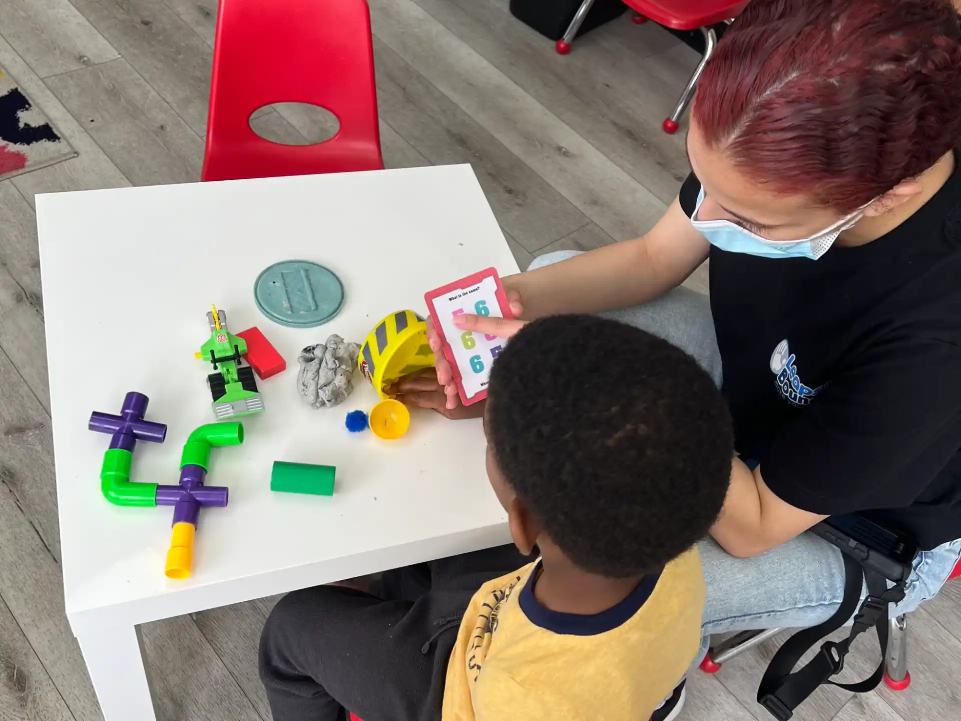 a person and a boy playing with toys on a table