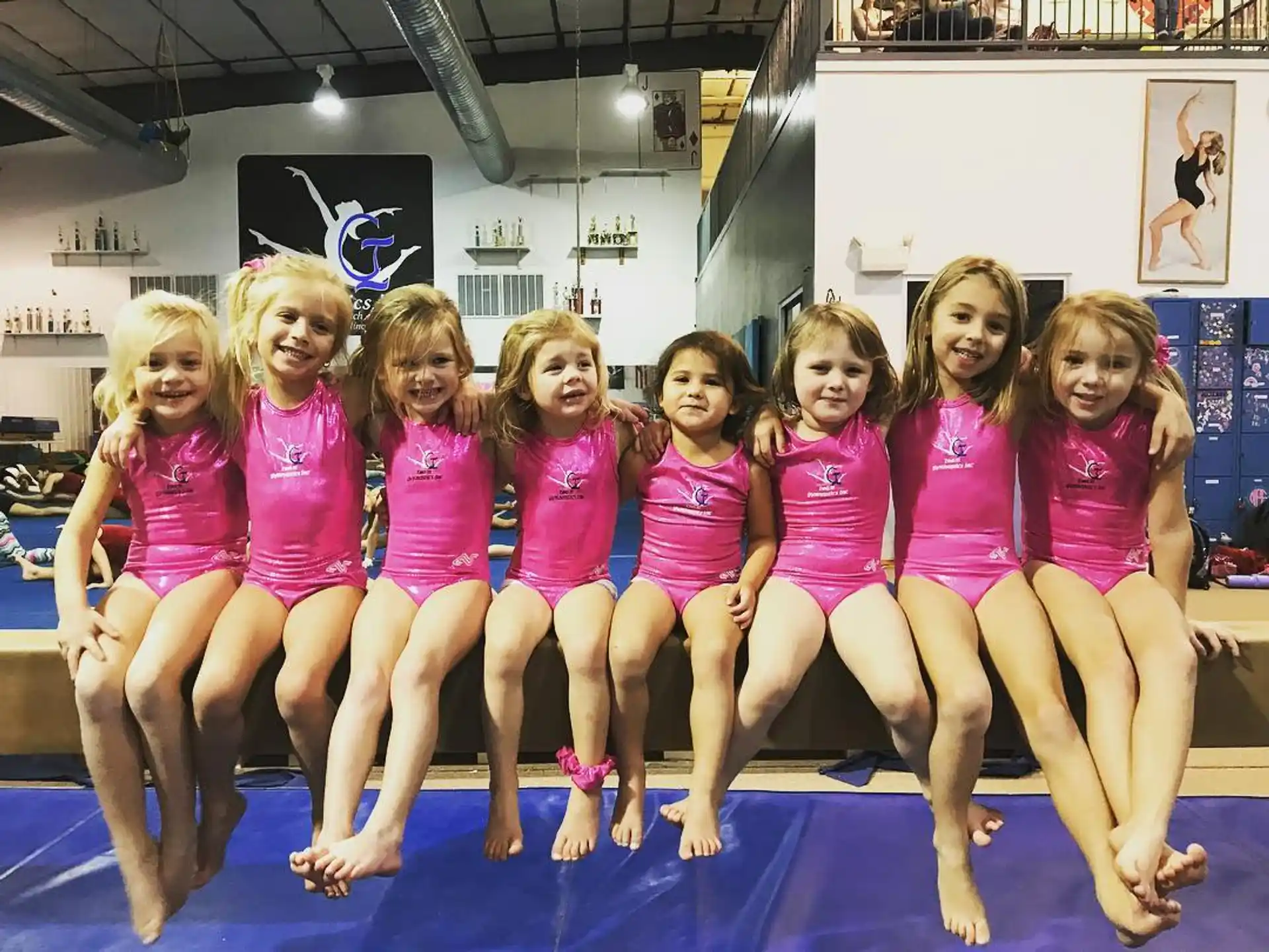 a group of girls in pink swimsuits sitting on a mat