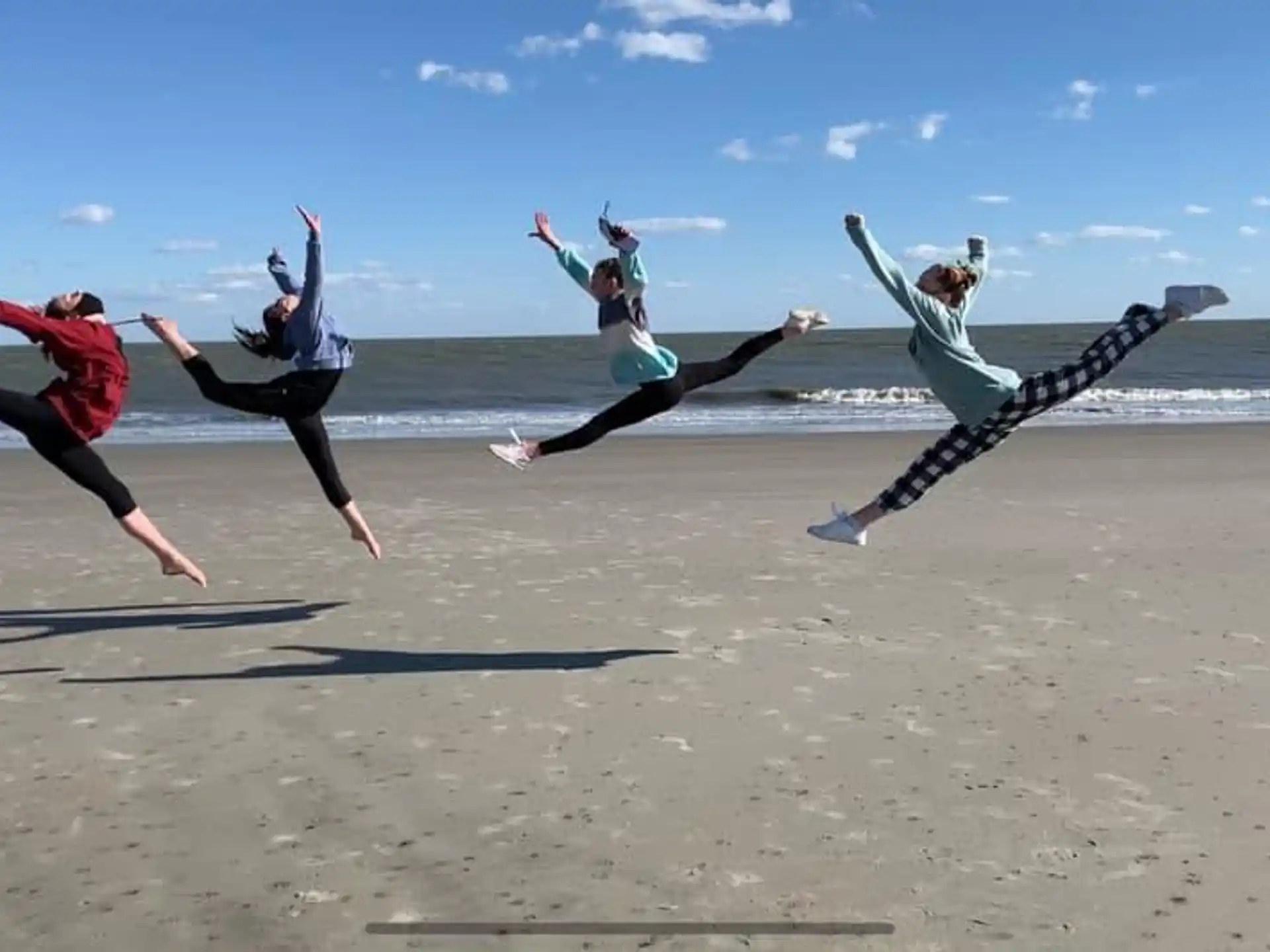 a group of women jumping on a beach