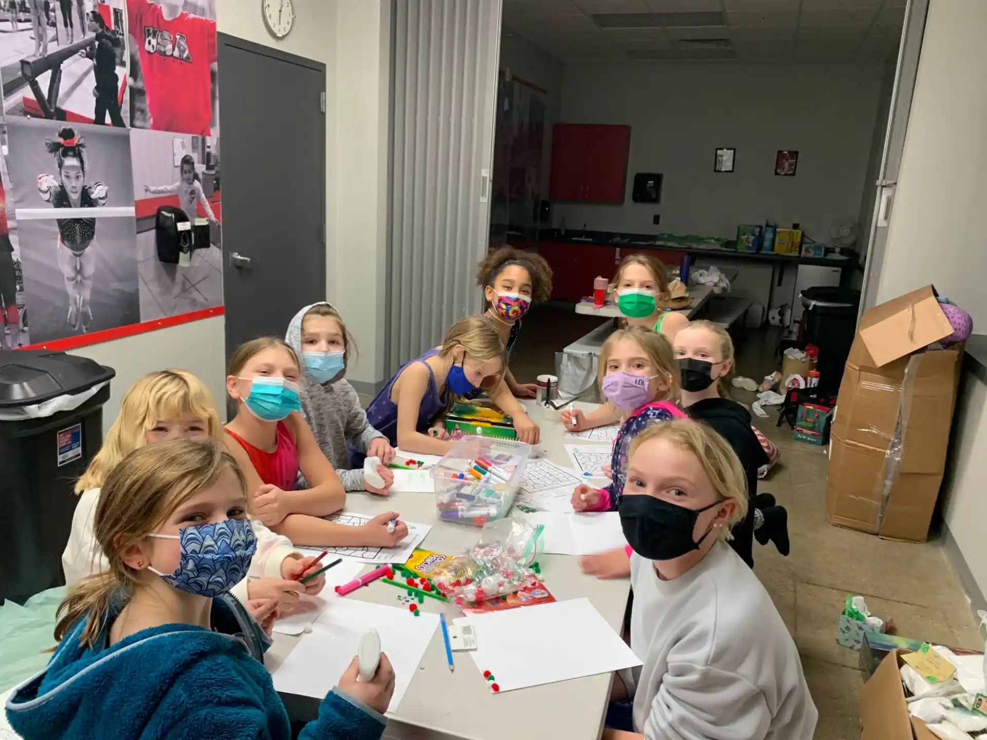 a group of children sitting around a table with a box of cookies