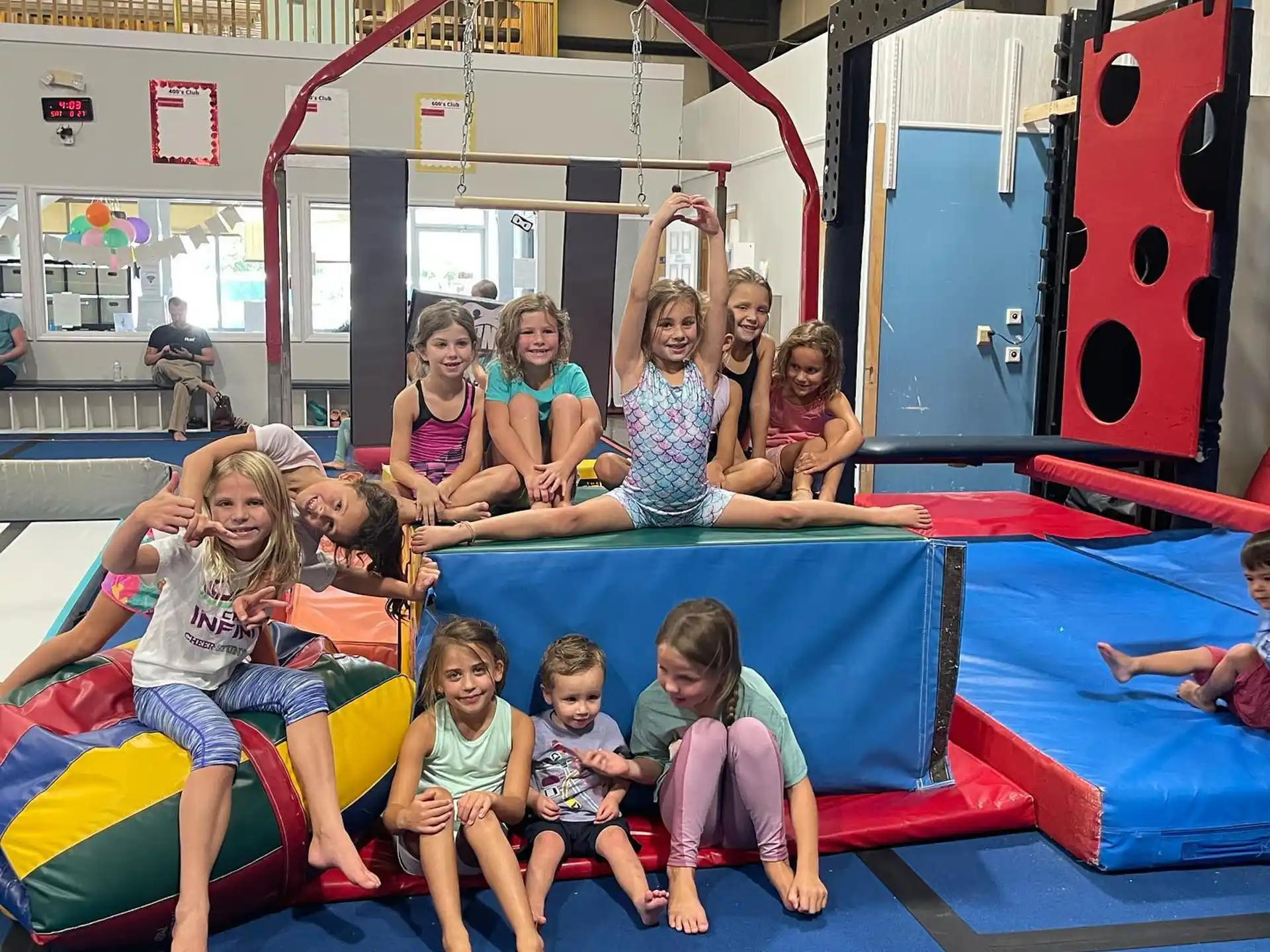 a group of children sitting on a blue mat in a room