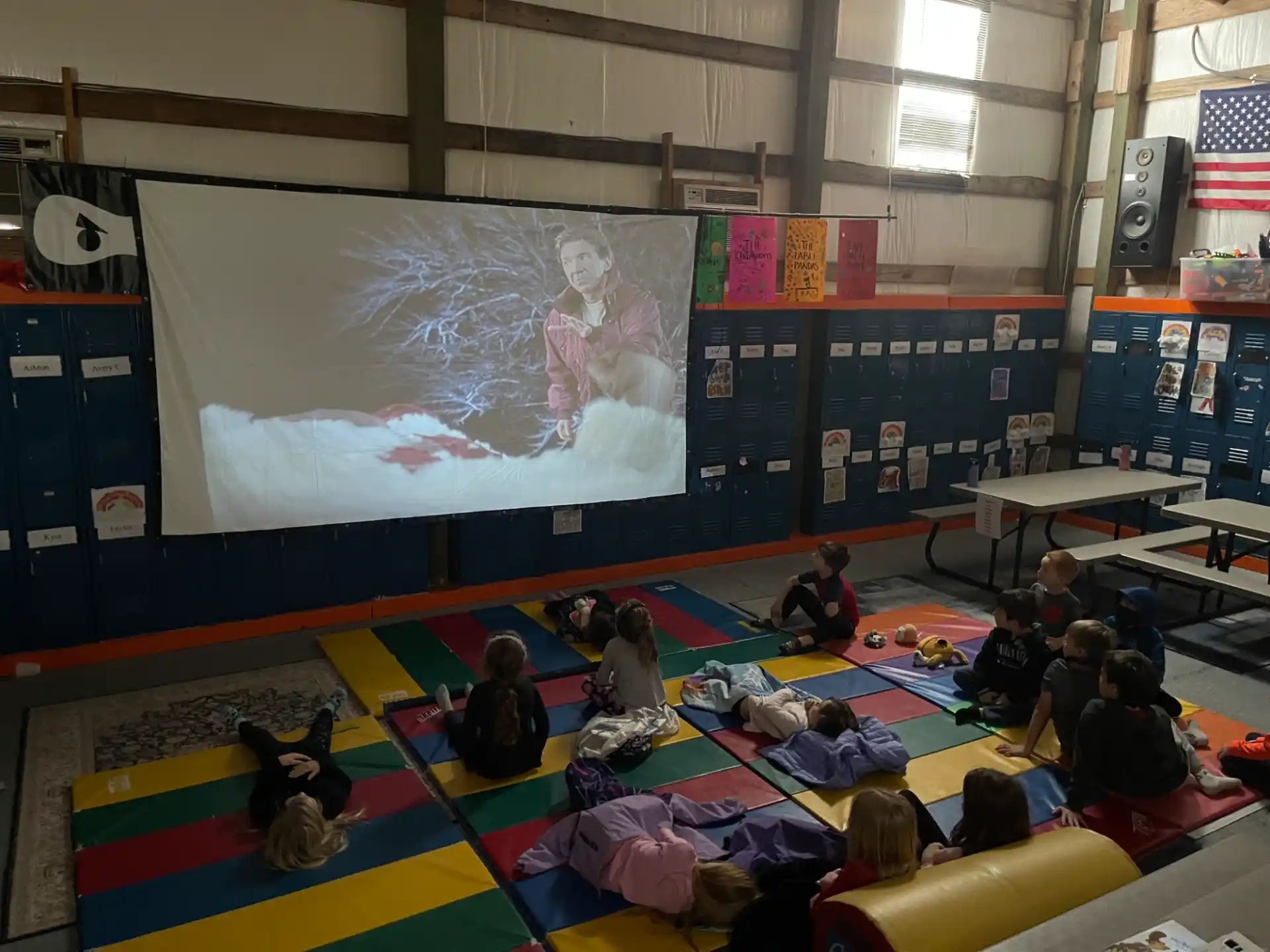 a group of people sitting in a room with a large screen