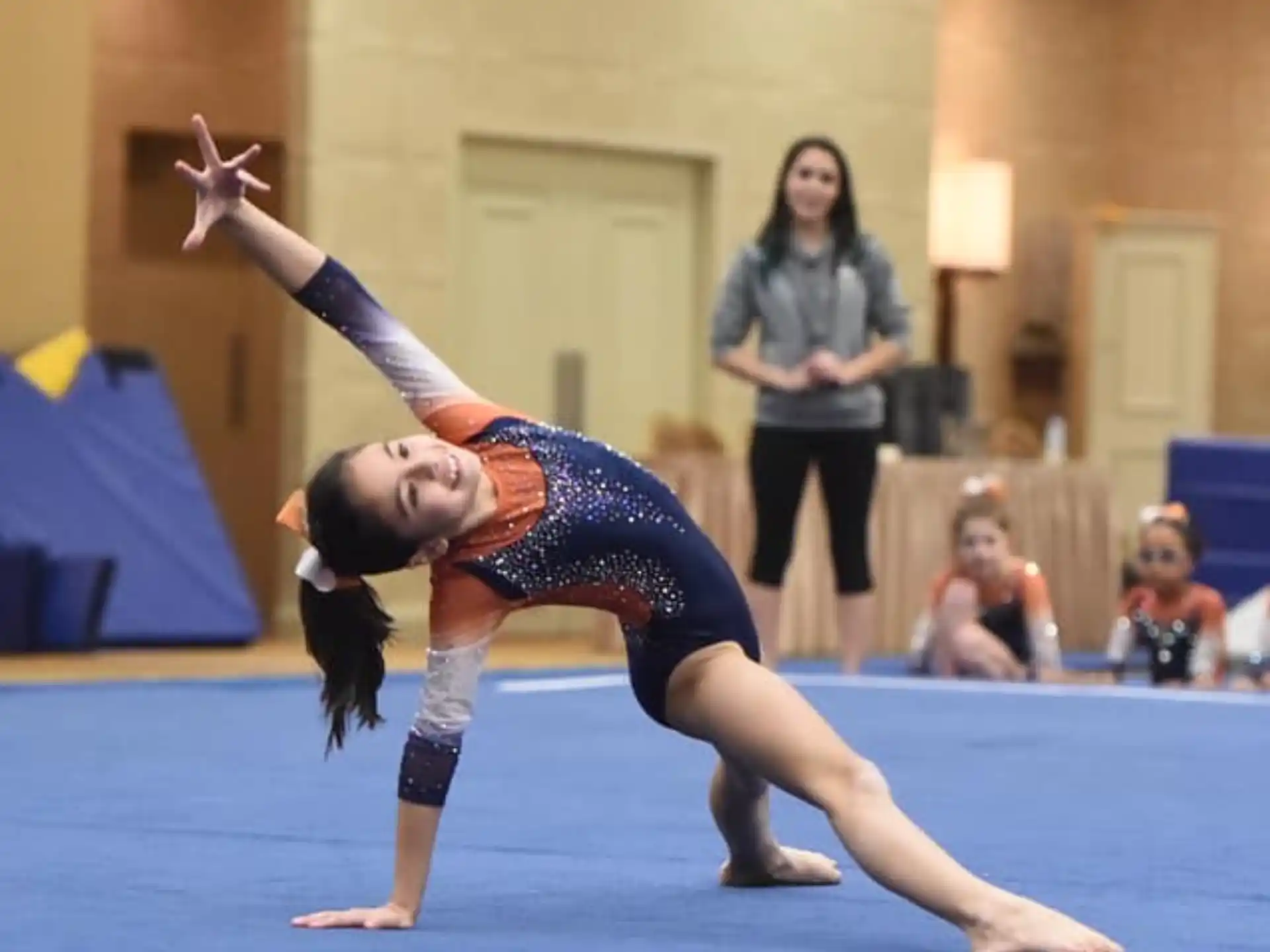 a person doing a handstand on a mat in a room with other people