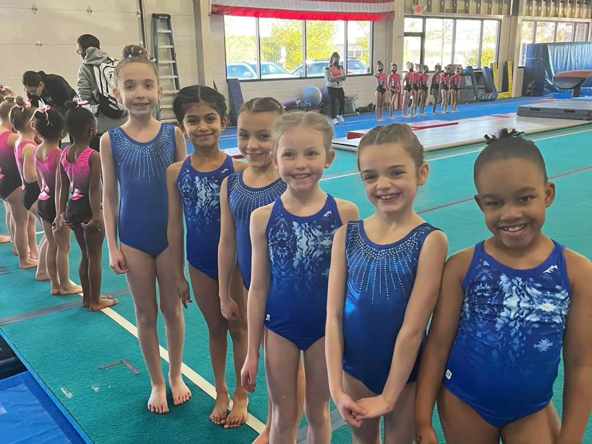 a group of children in blue swimsuits standing in a pool