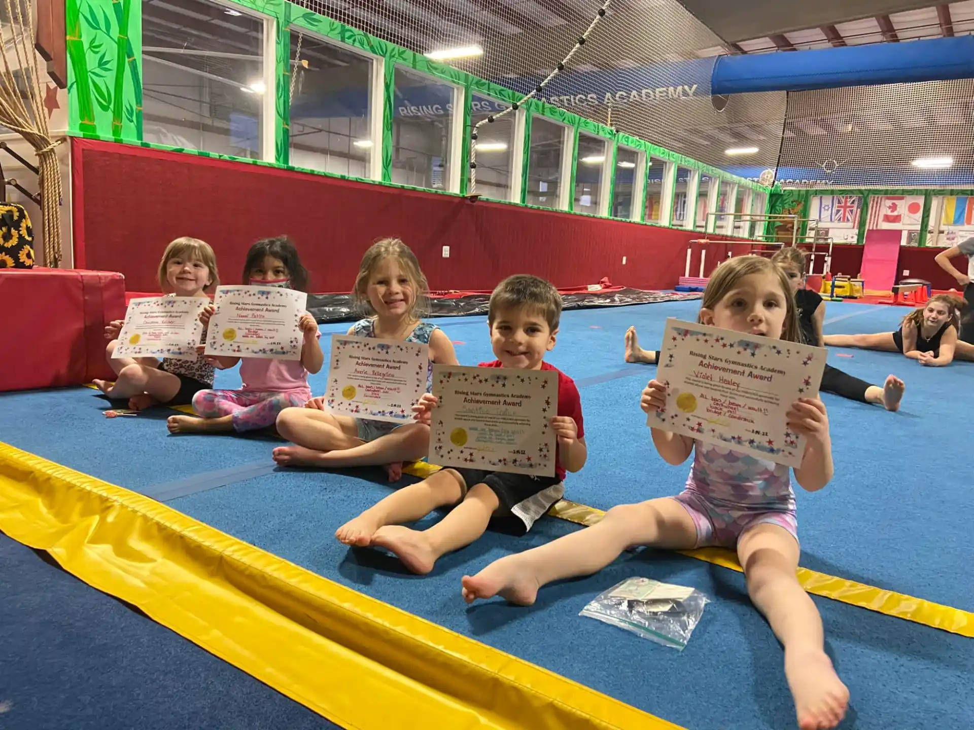 children sitting on a mat holding signs