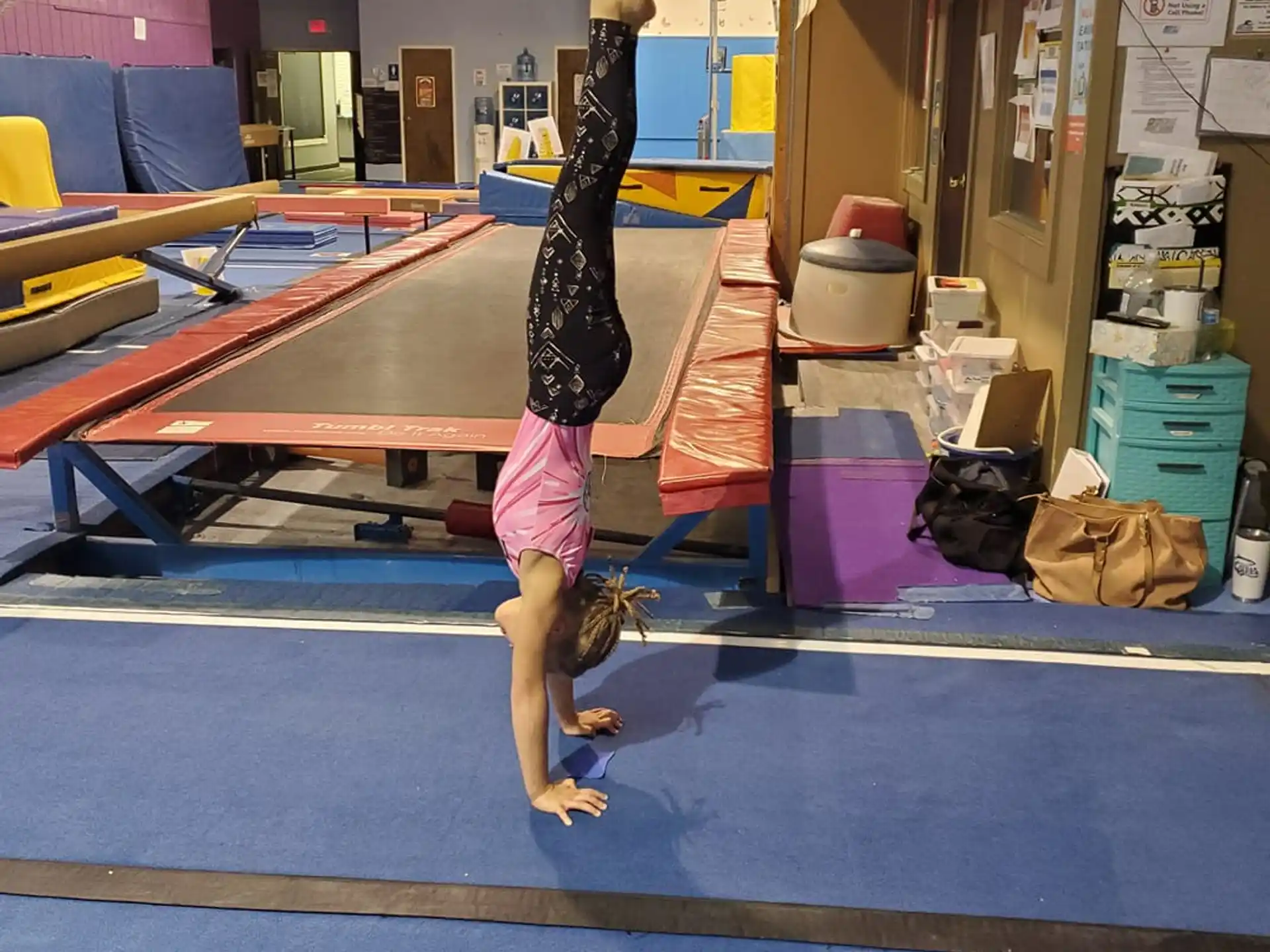 a girl doing a handstand on a mat in a gym