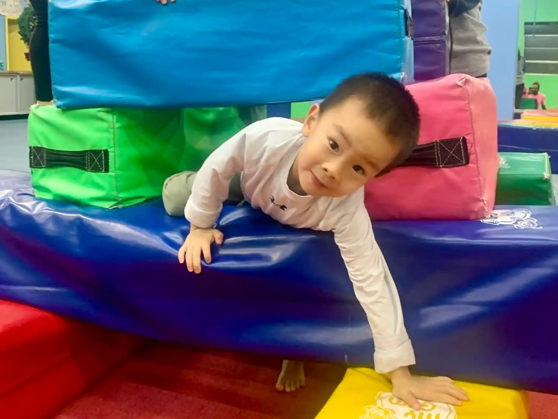 a baby lying on a red and yellow toy on a red carpet