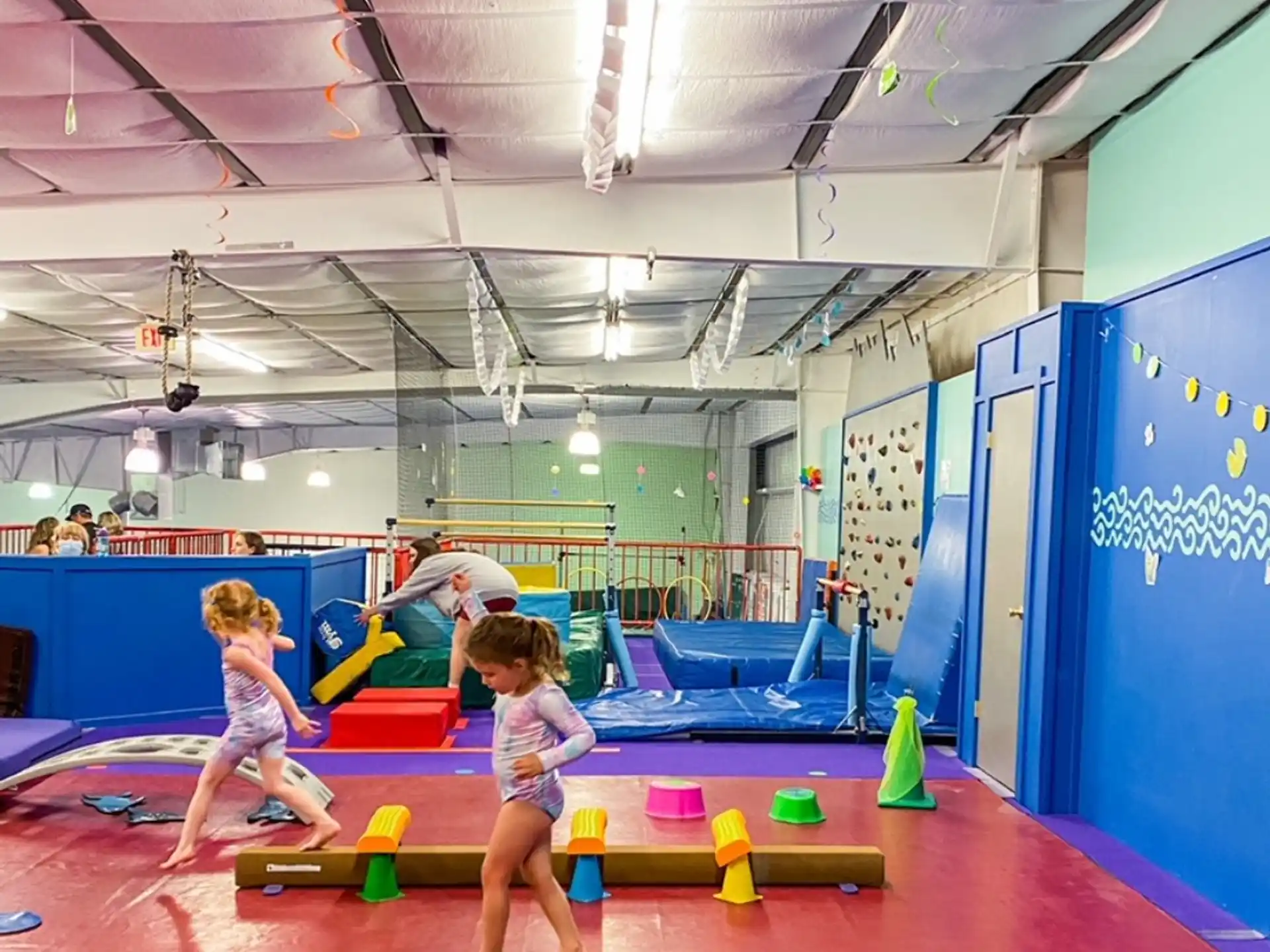 a couple of kids playing on a mat in a gym