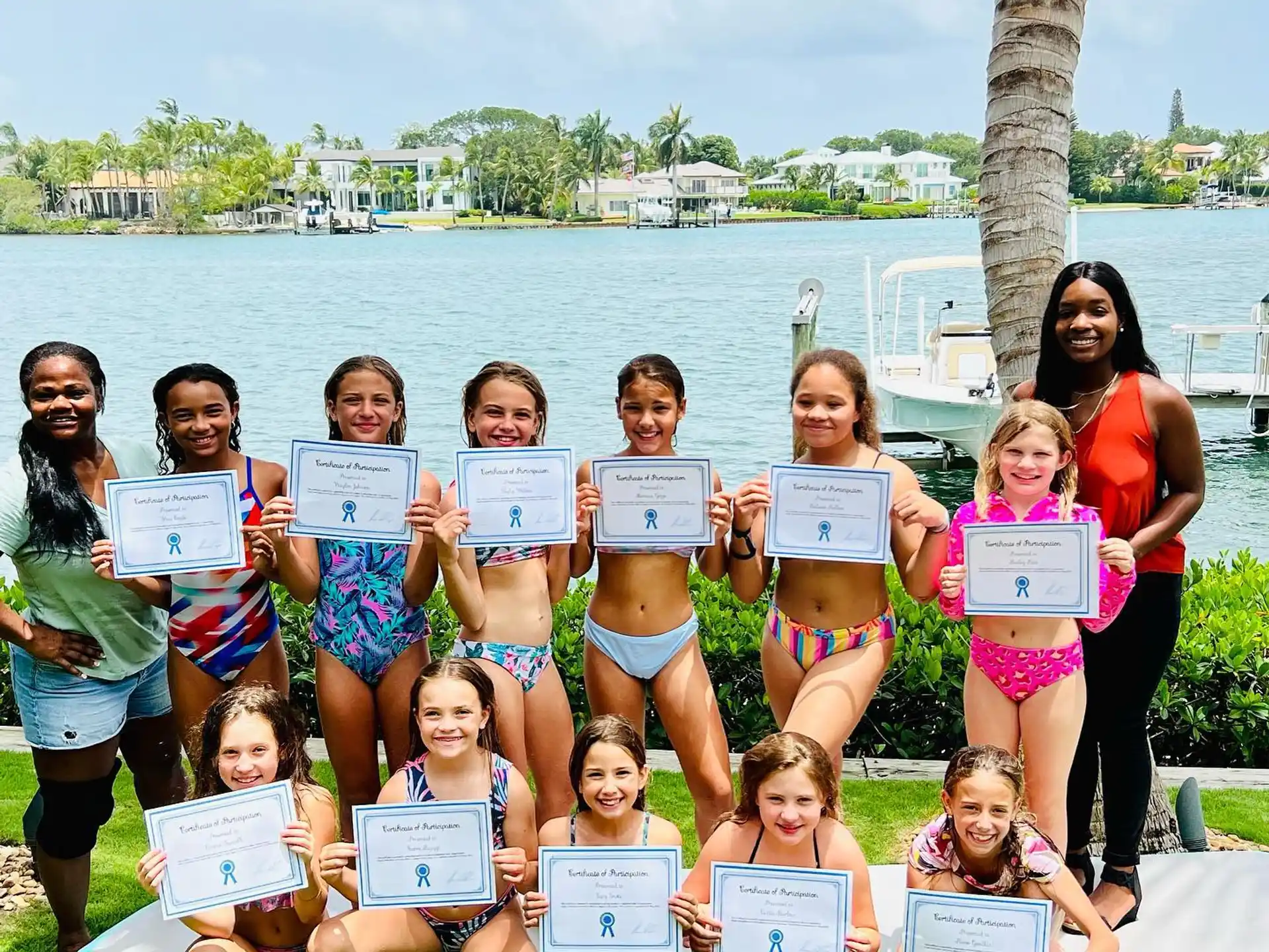 a group of people posing for a photo with signs in front of a body of water