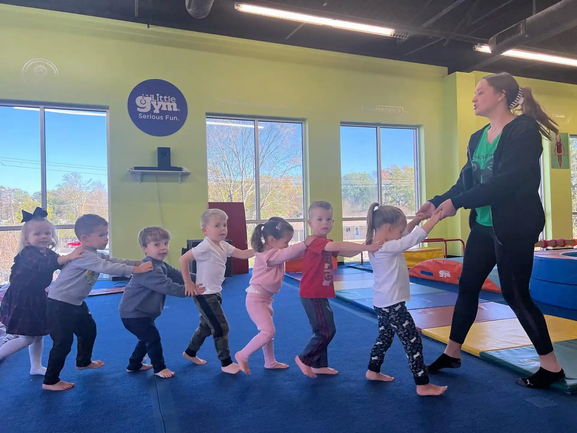 a person and a group of children dancing in a room