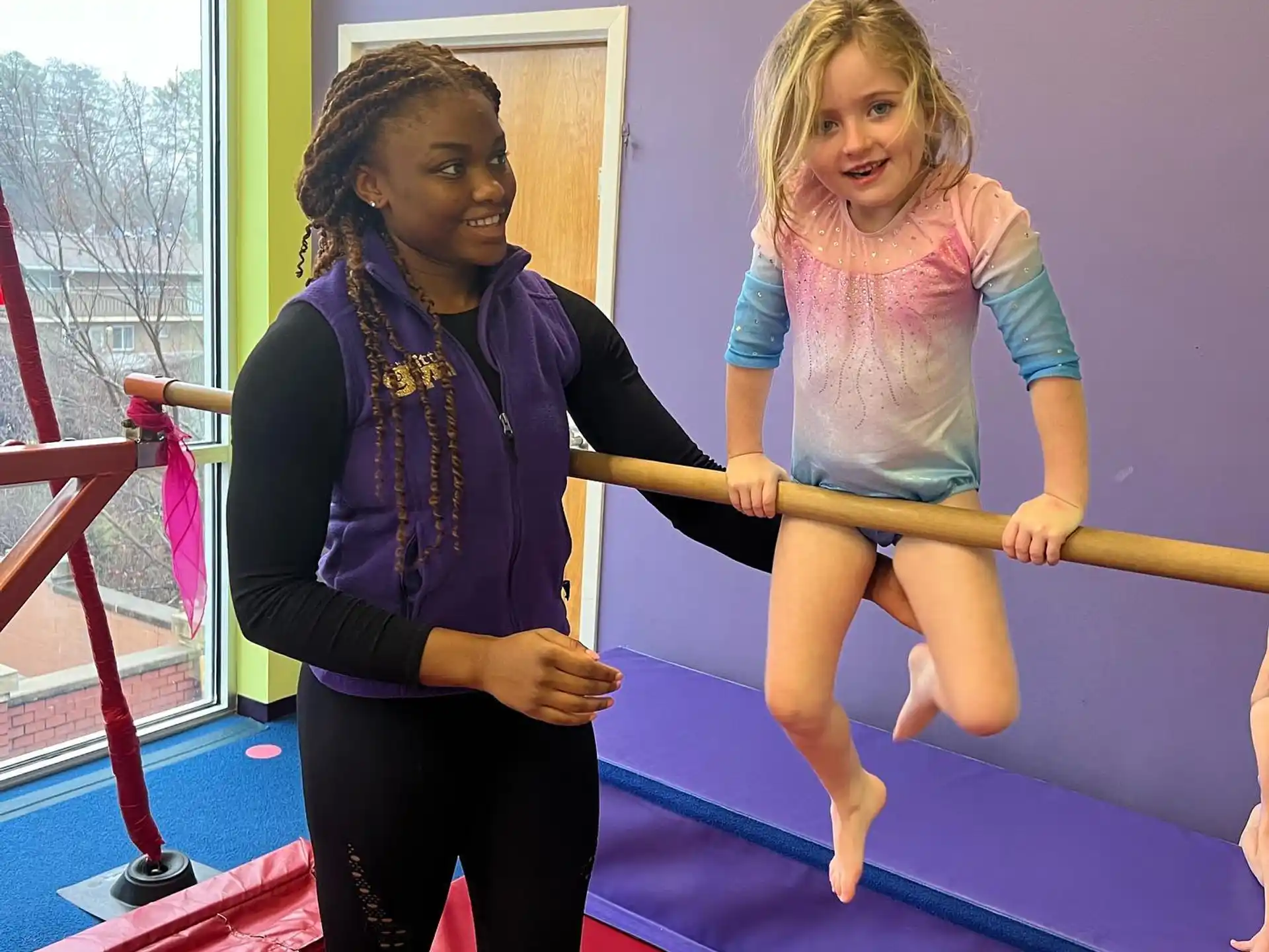 a person holding a girl on a red mat