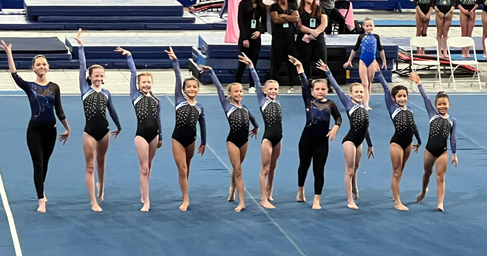 a group of women in black and white leotards on a blue mat