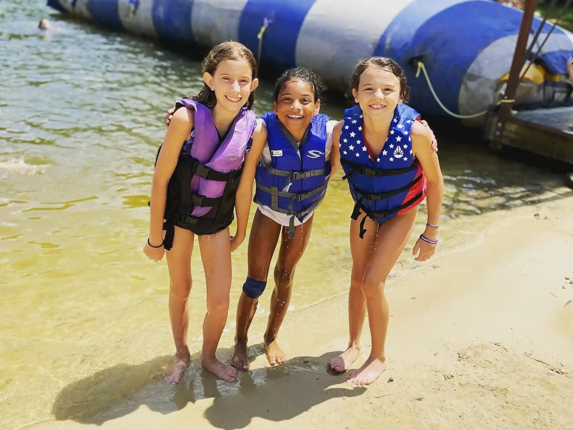 a group of girls in swimsuits standing on a beach