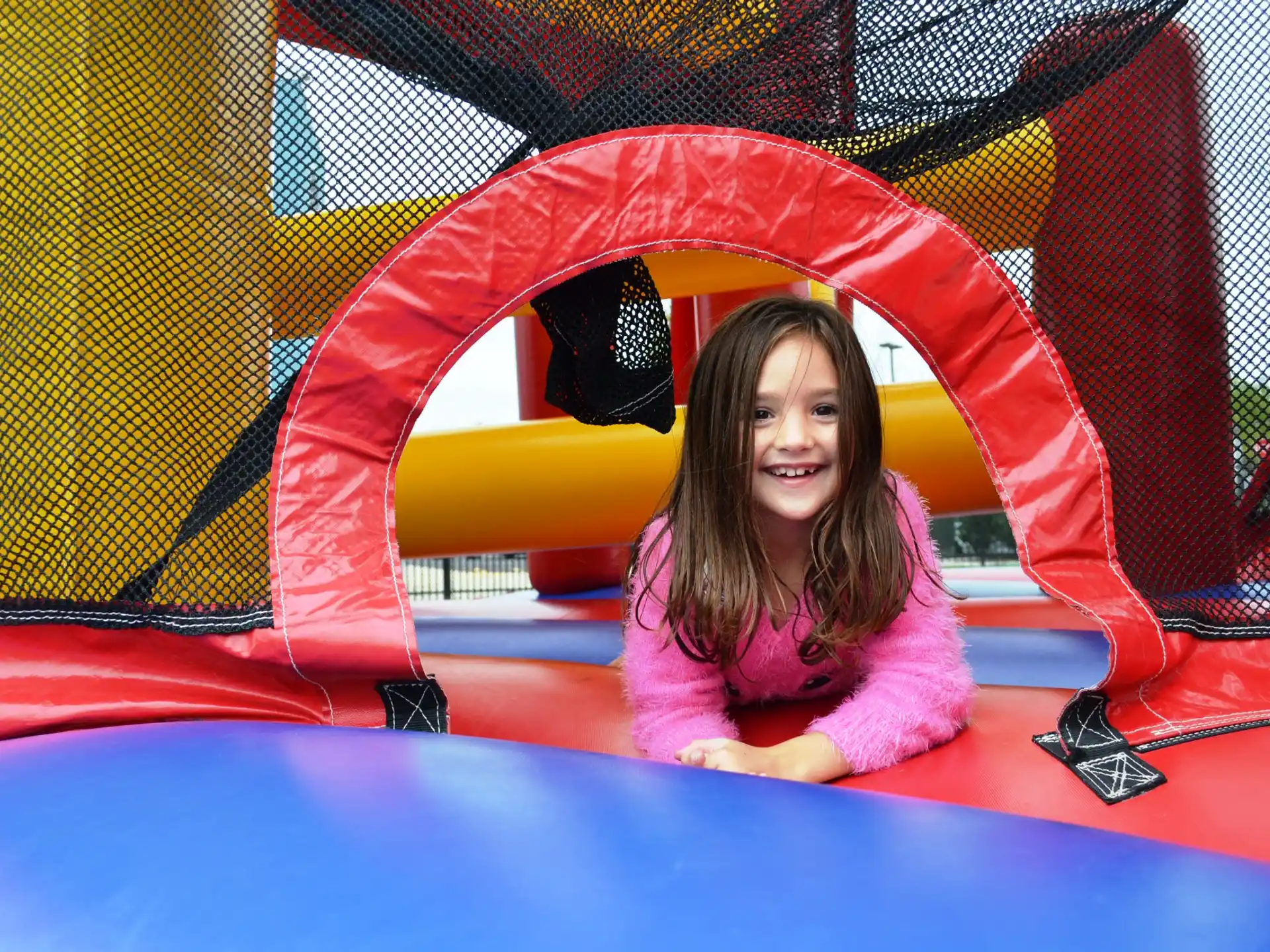 a girl sitting in a large red and yellow slide