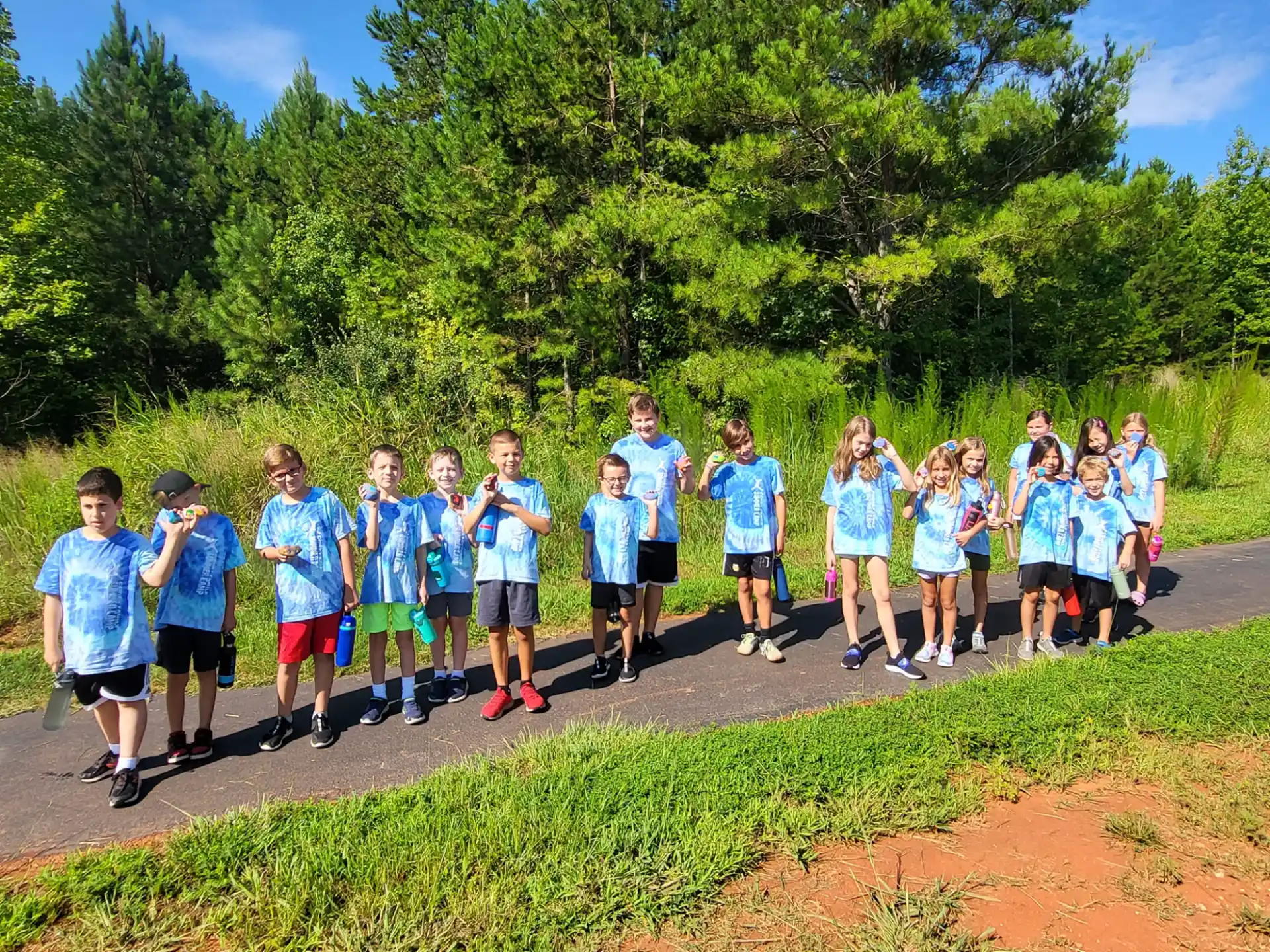 a group of people wearing matching t-shirts and running on a dirt road