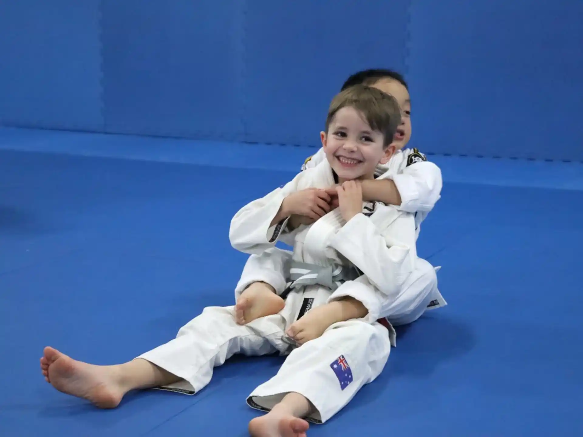 a boy and a girl in karate uniforms sitting on the ground