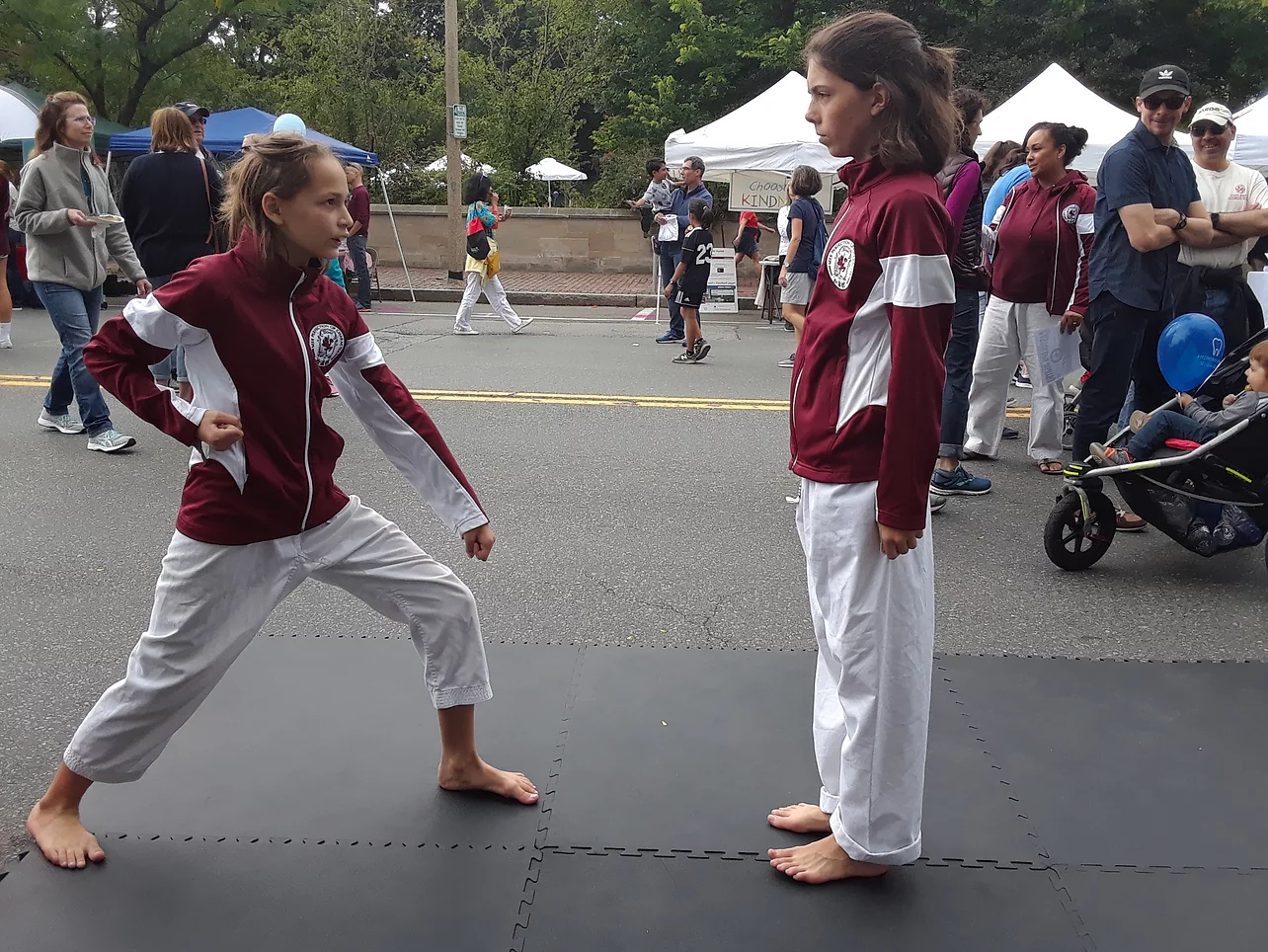 a couple of girls in red karate uniforms walking on a street