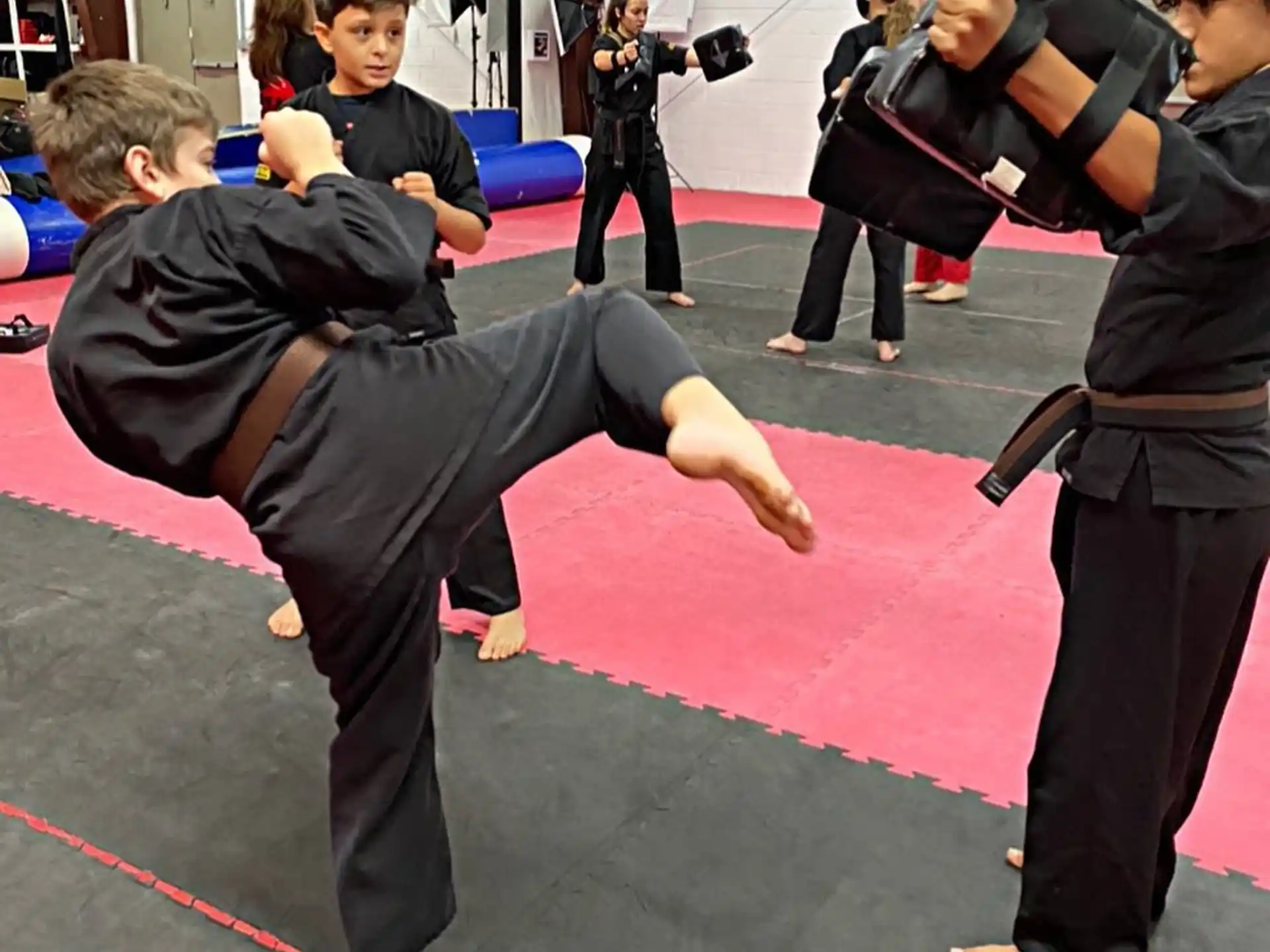 a person doing a handstand on a mat in a room with other people