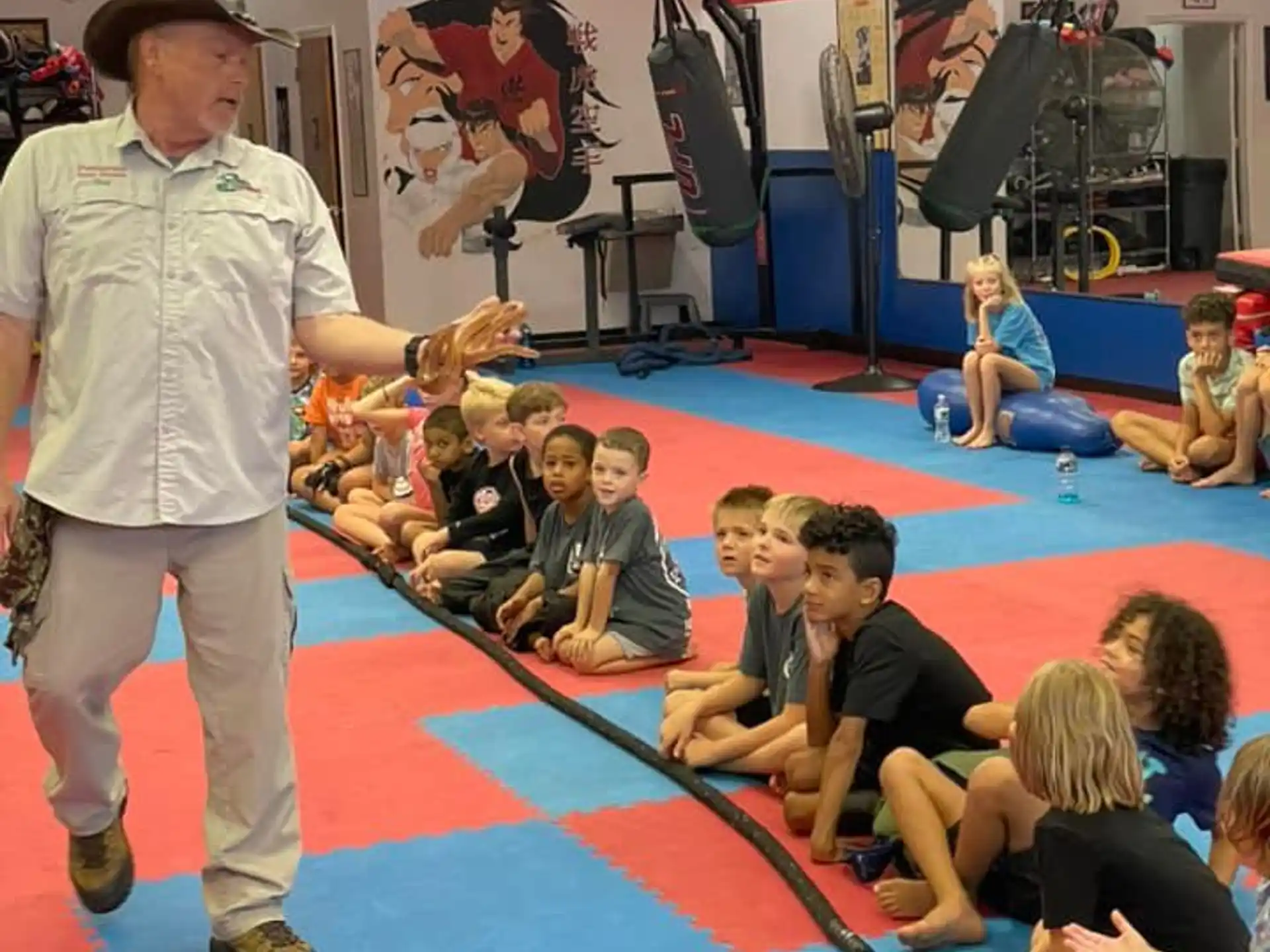 a person standing in front of a group of children sitting on the floor