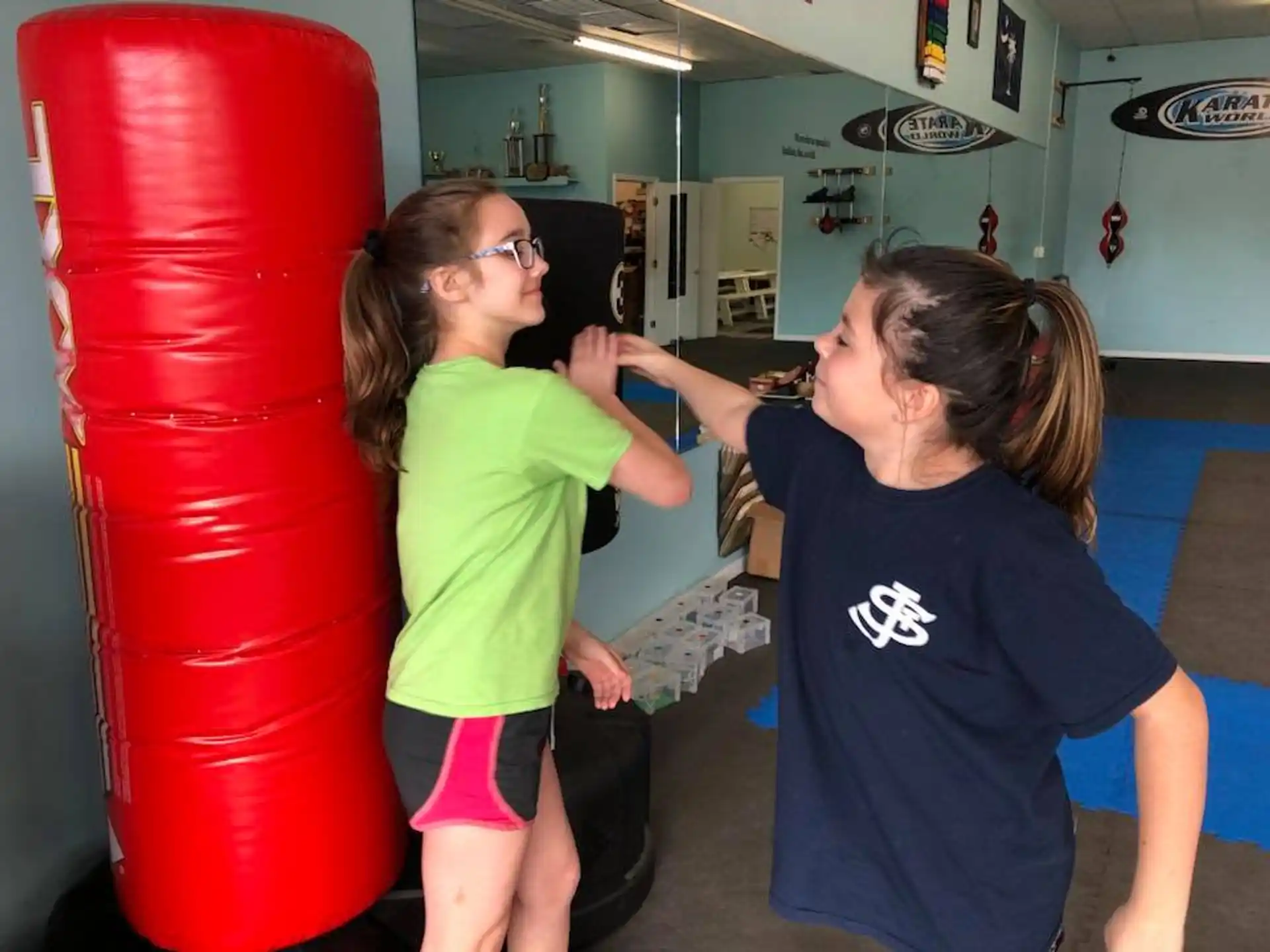 a couple of girls playing with a red punching bag